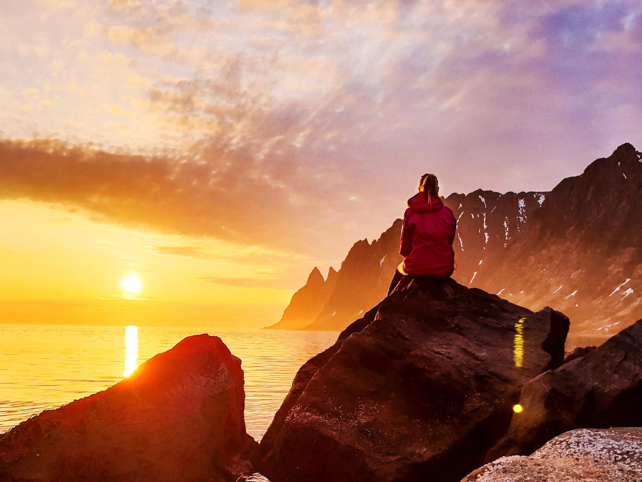 A person watching the midnight sun at Senja in Northern Norway