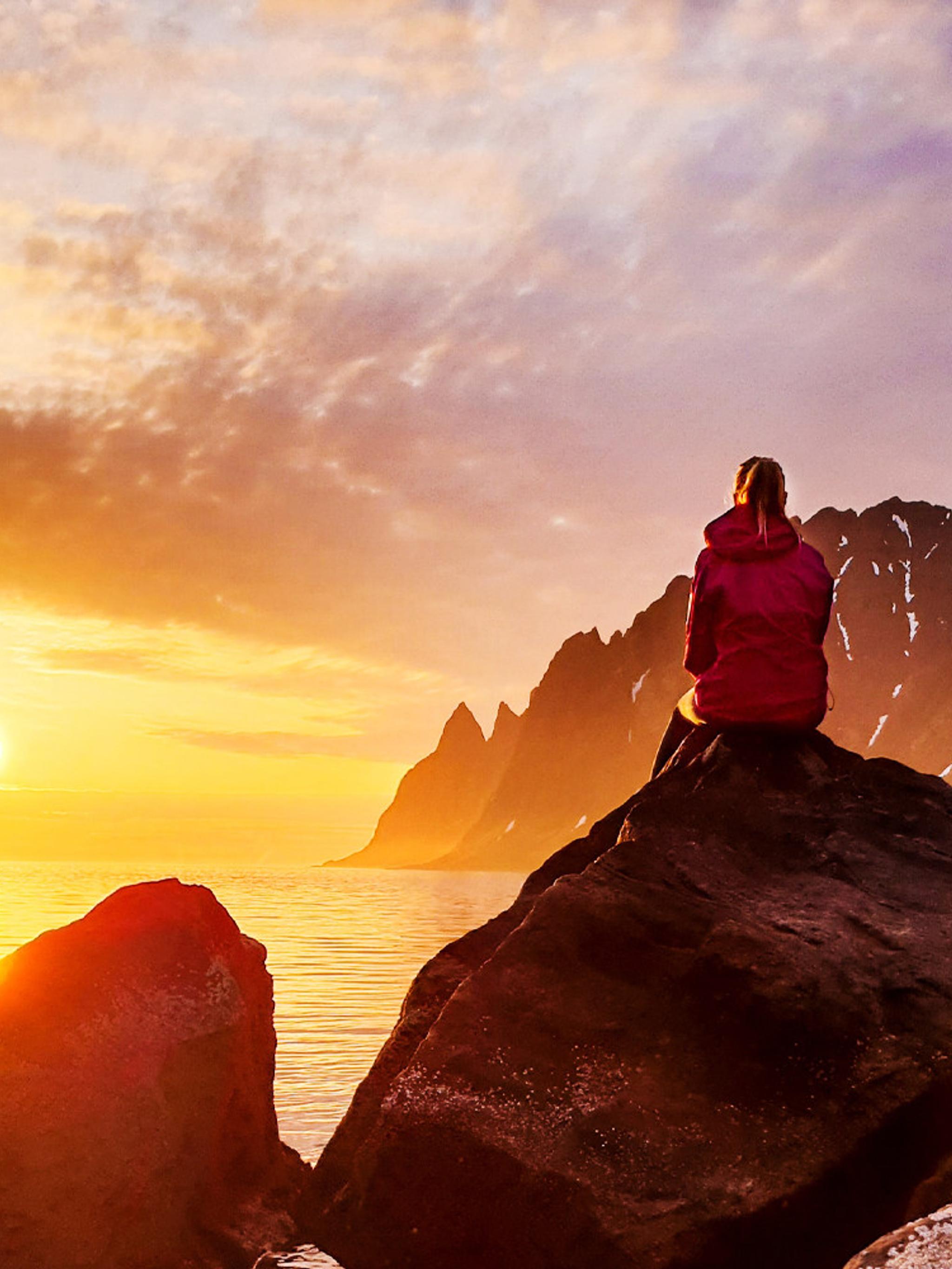 A person watching the midnight sun at Senja in Northern Norway