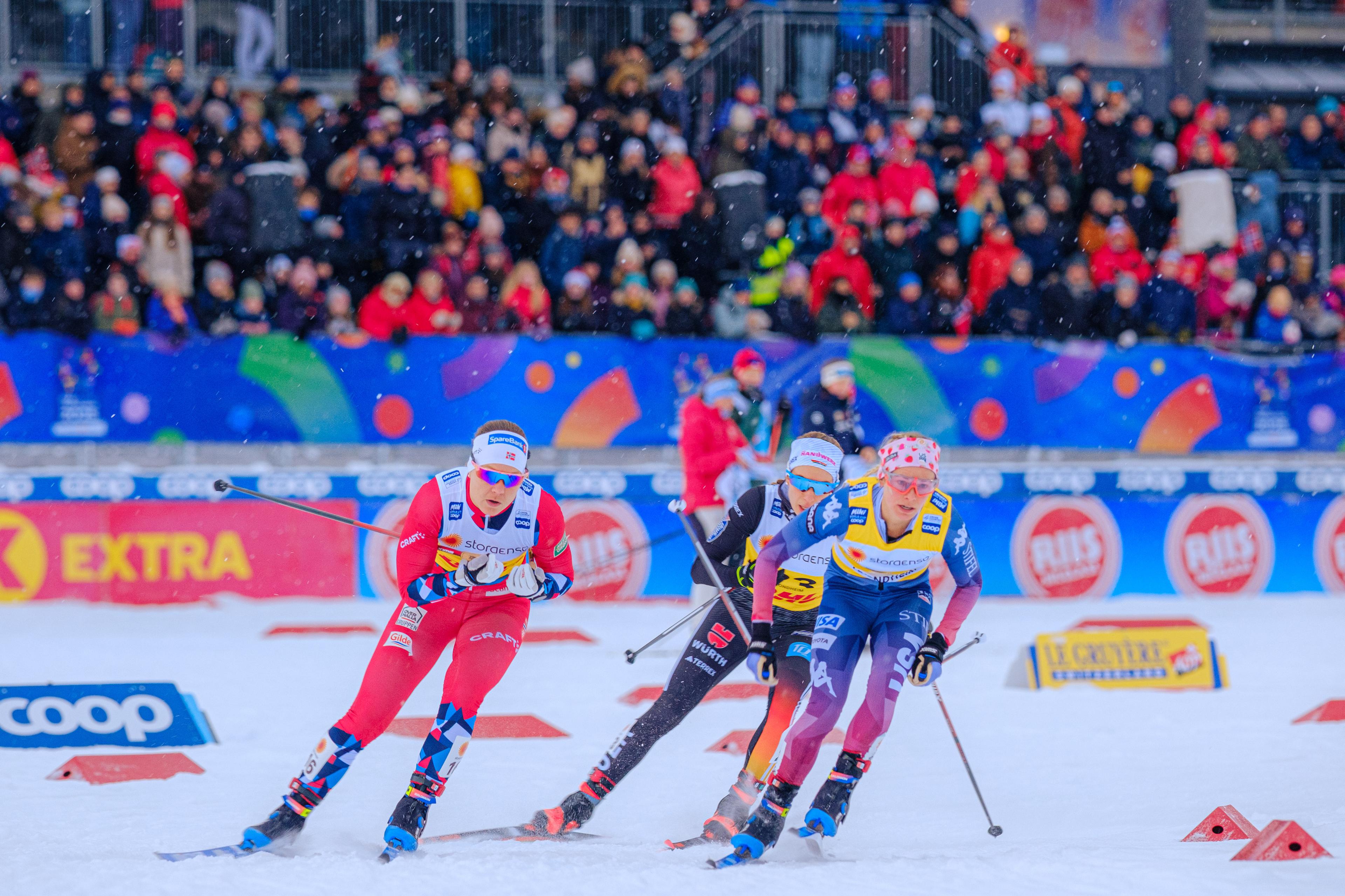Woman in a skiing competition in front of a stand full of people.
