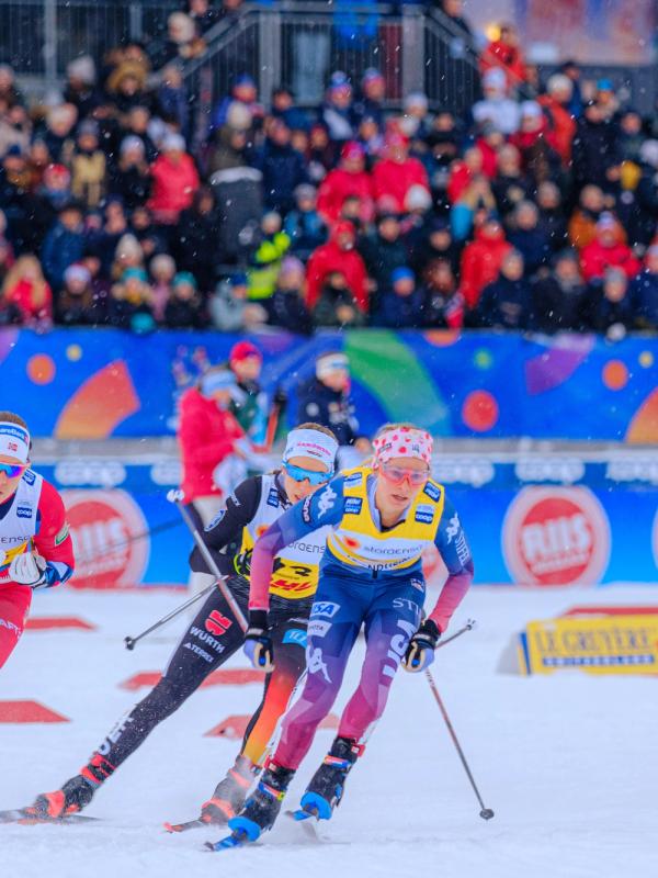 Woman in a skiing competition in front of a stand full of people.