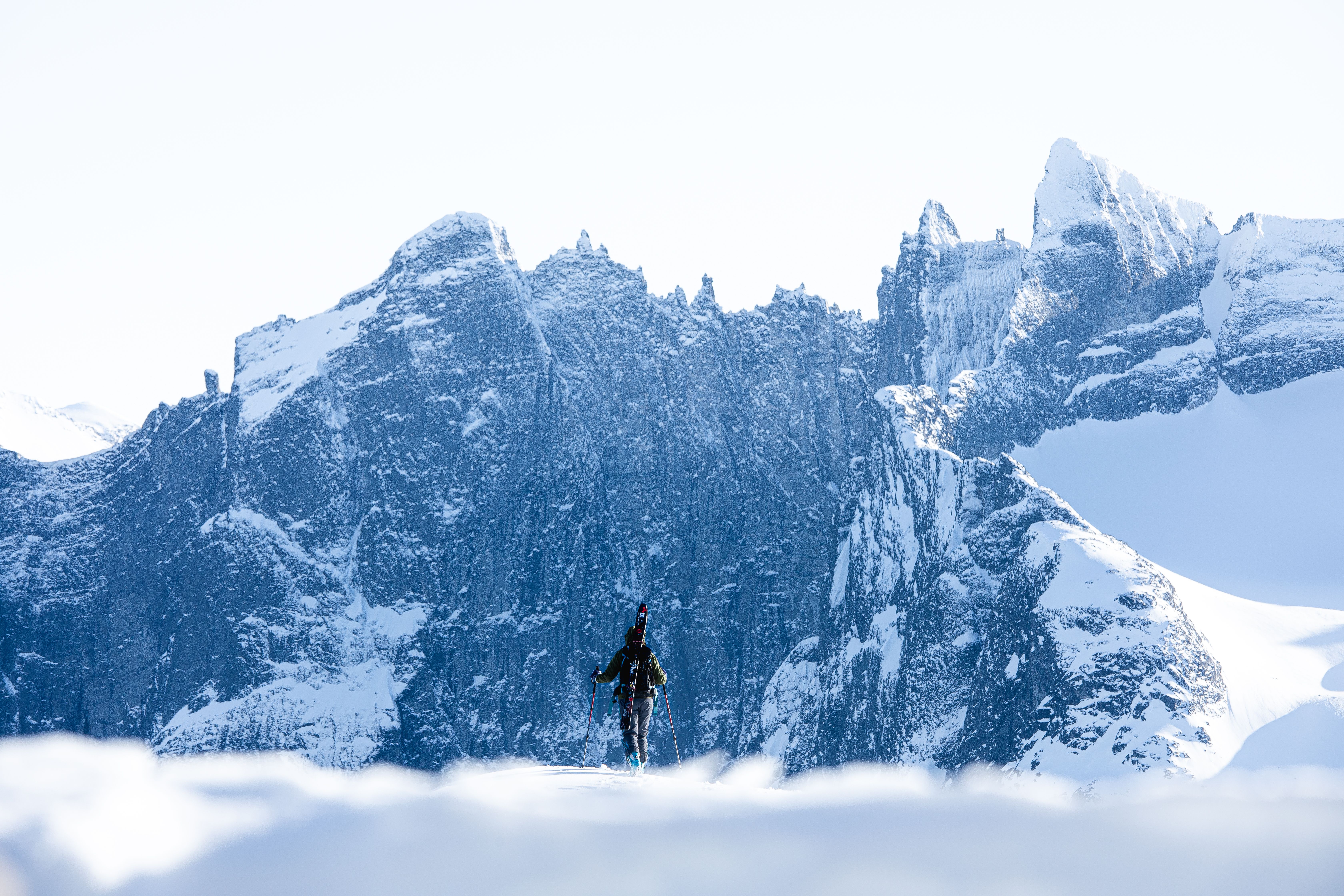 A person with skies looking at Trollveggen in Winter