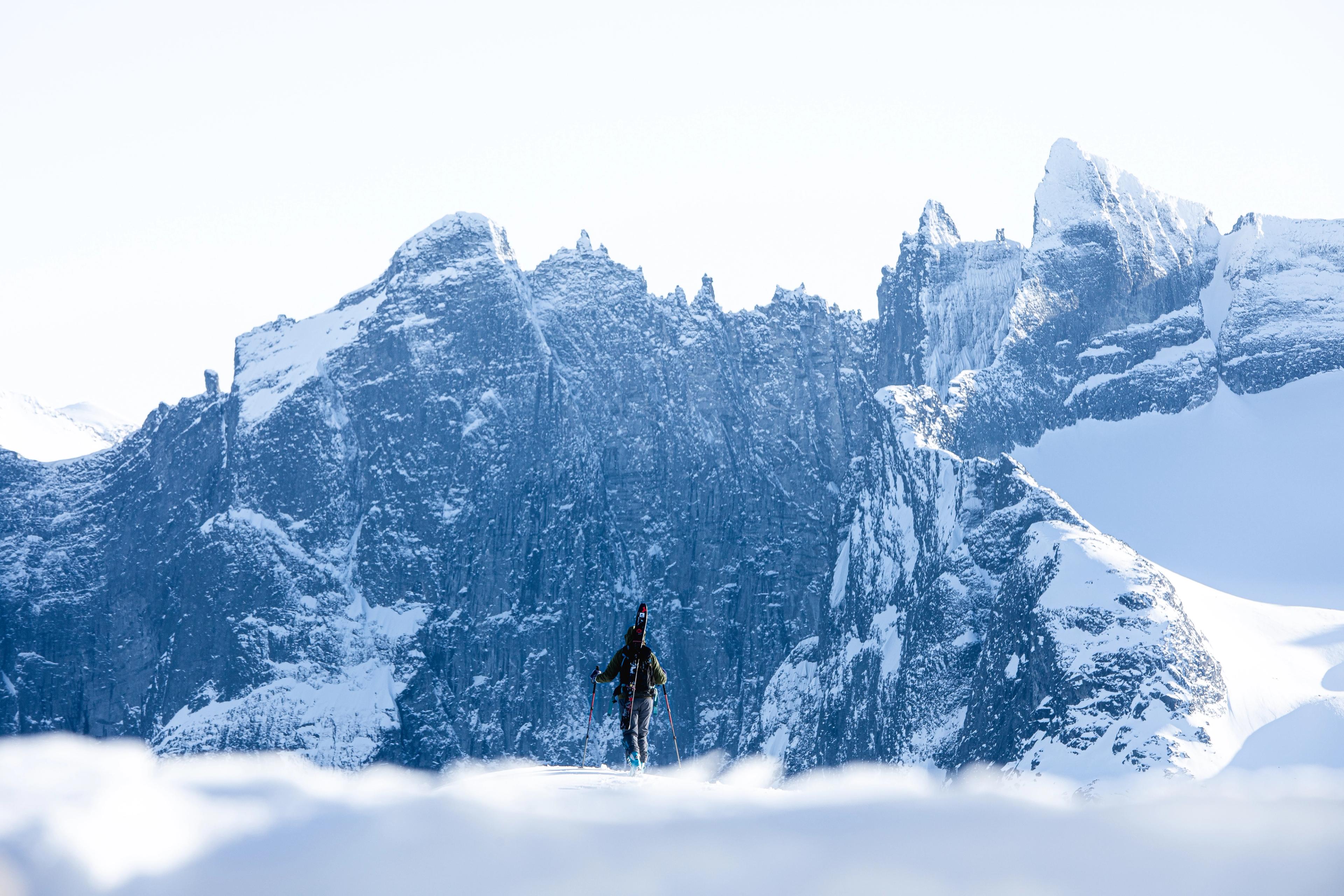 A person with skies looking at Trollveggen in Winter