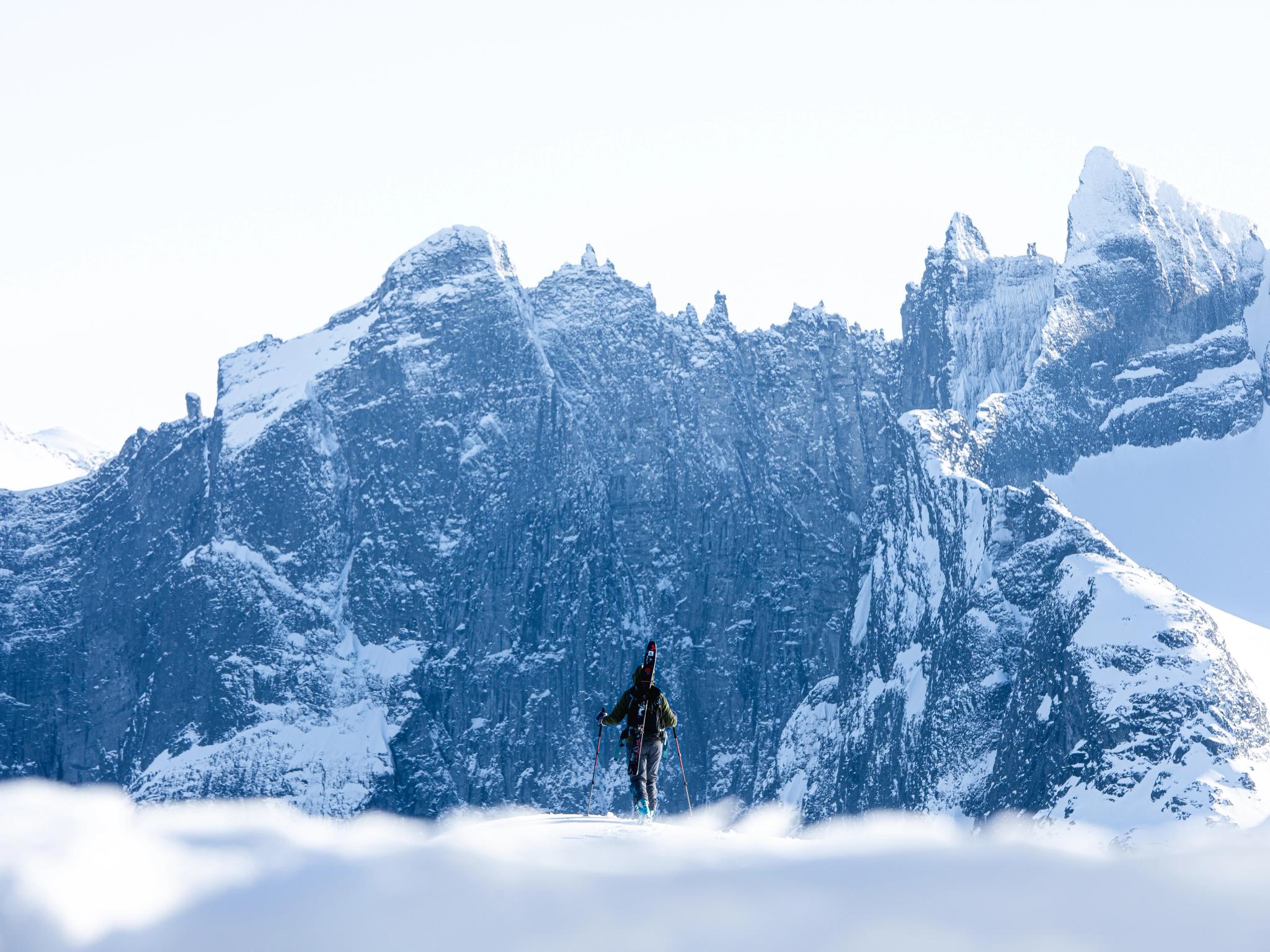 A person with skies looking at Trollveggen in Winter