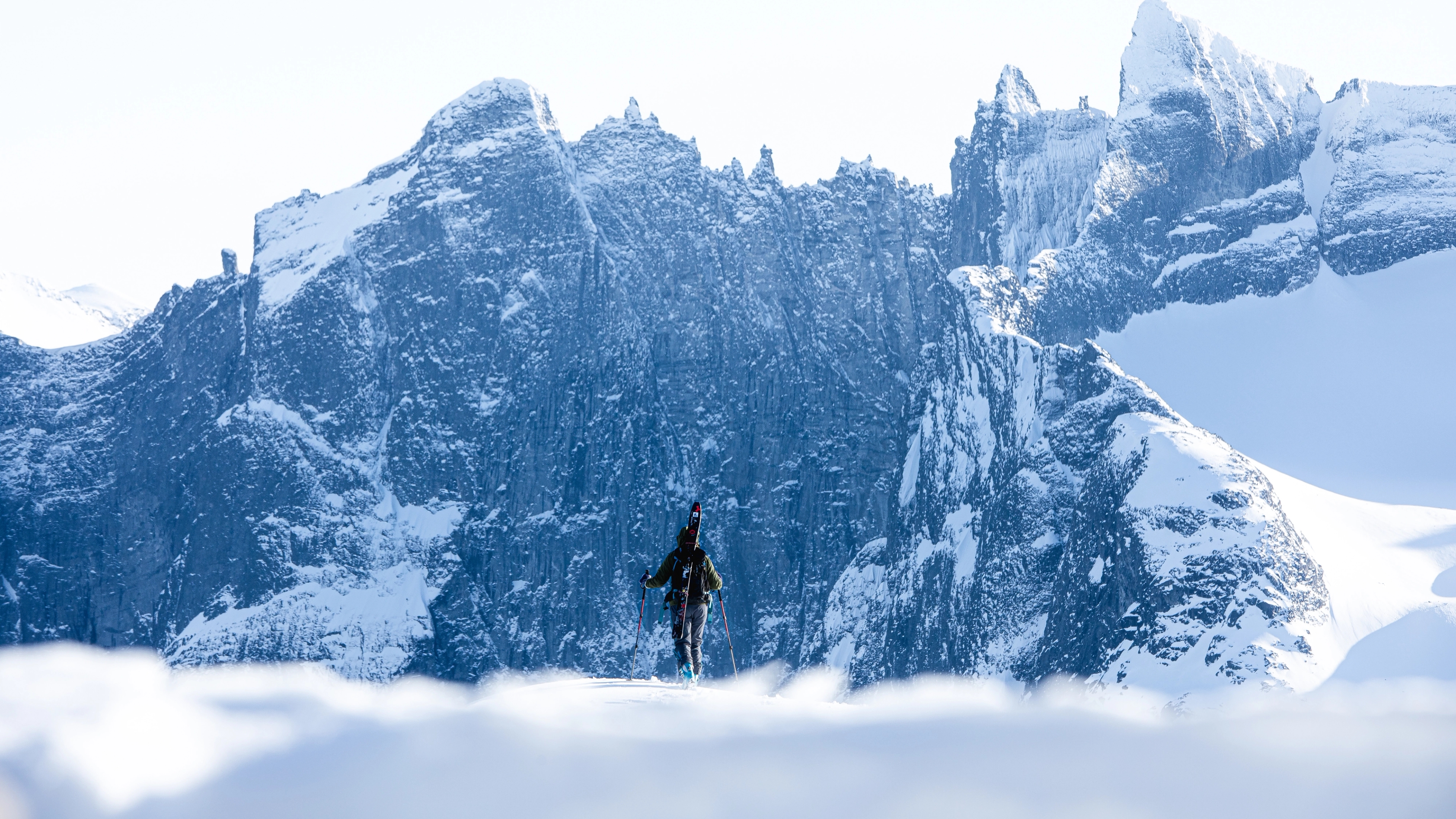 A person with skies looking at Trollveggen in Winter