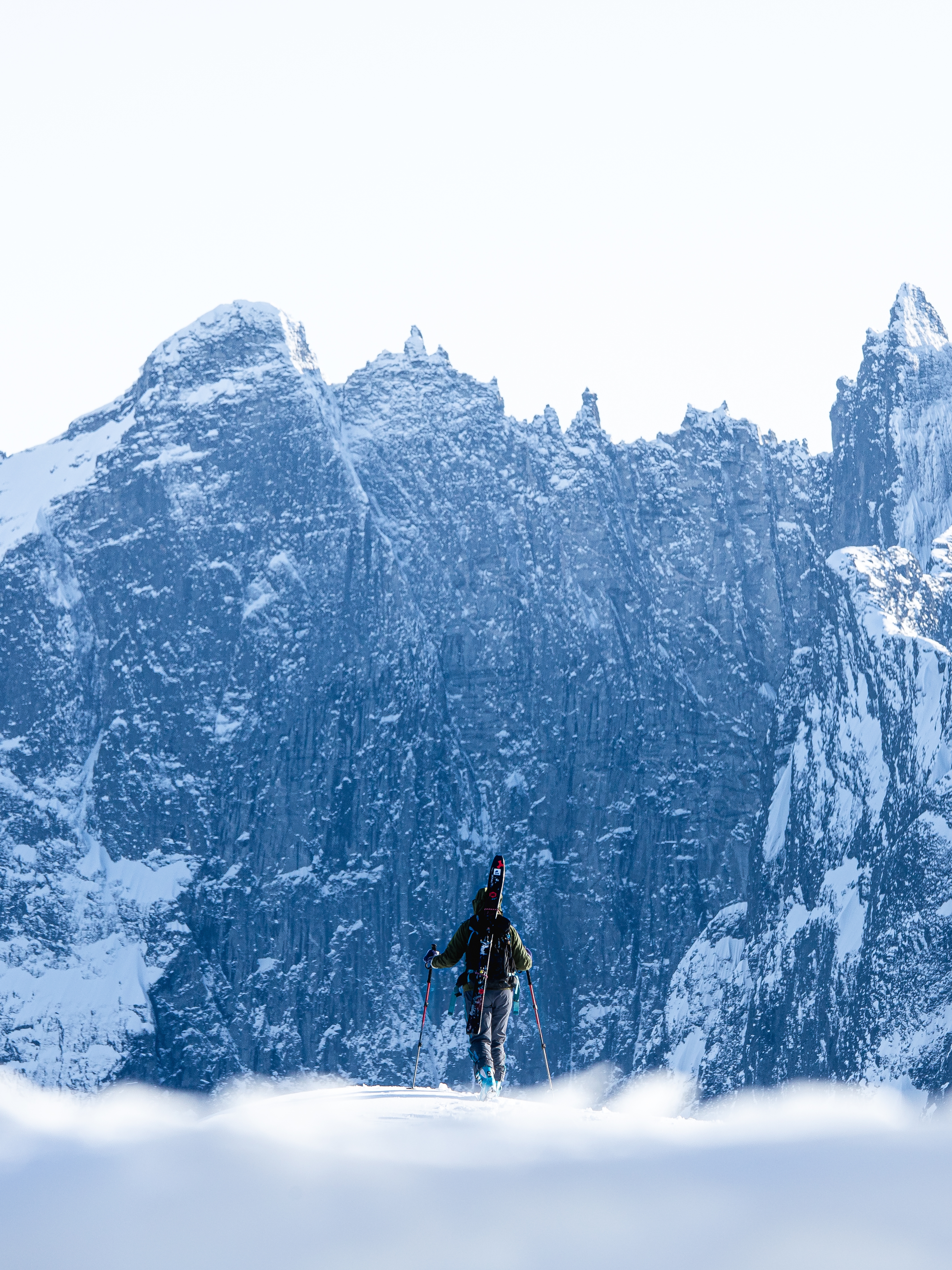 A person with skies looking at Trollveggen in Winter