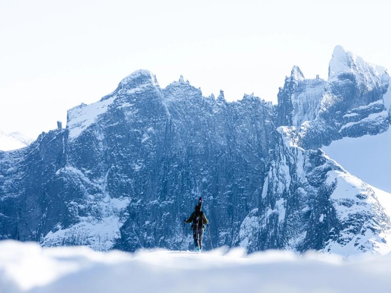 A person with skies looking at Trollveggen in Winter
