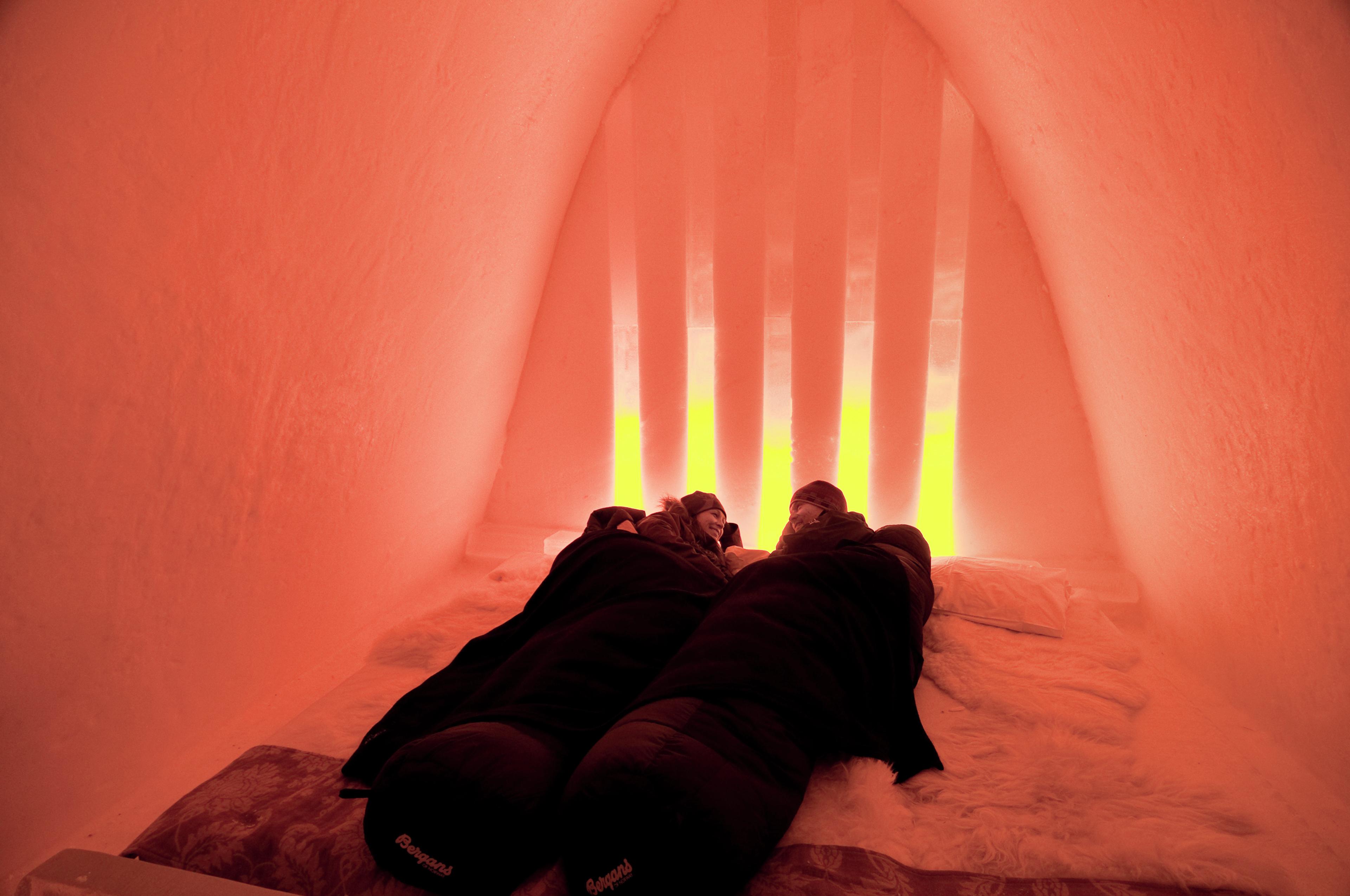 Two people under raindeer skins in the Snow Hotel in Hunderfossen Winter Park, Eastern Norway