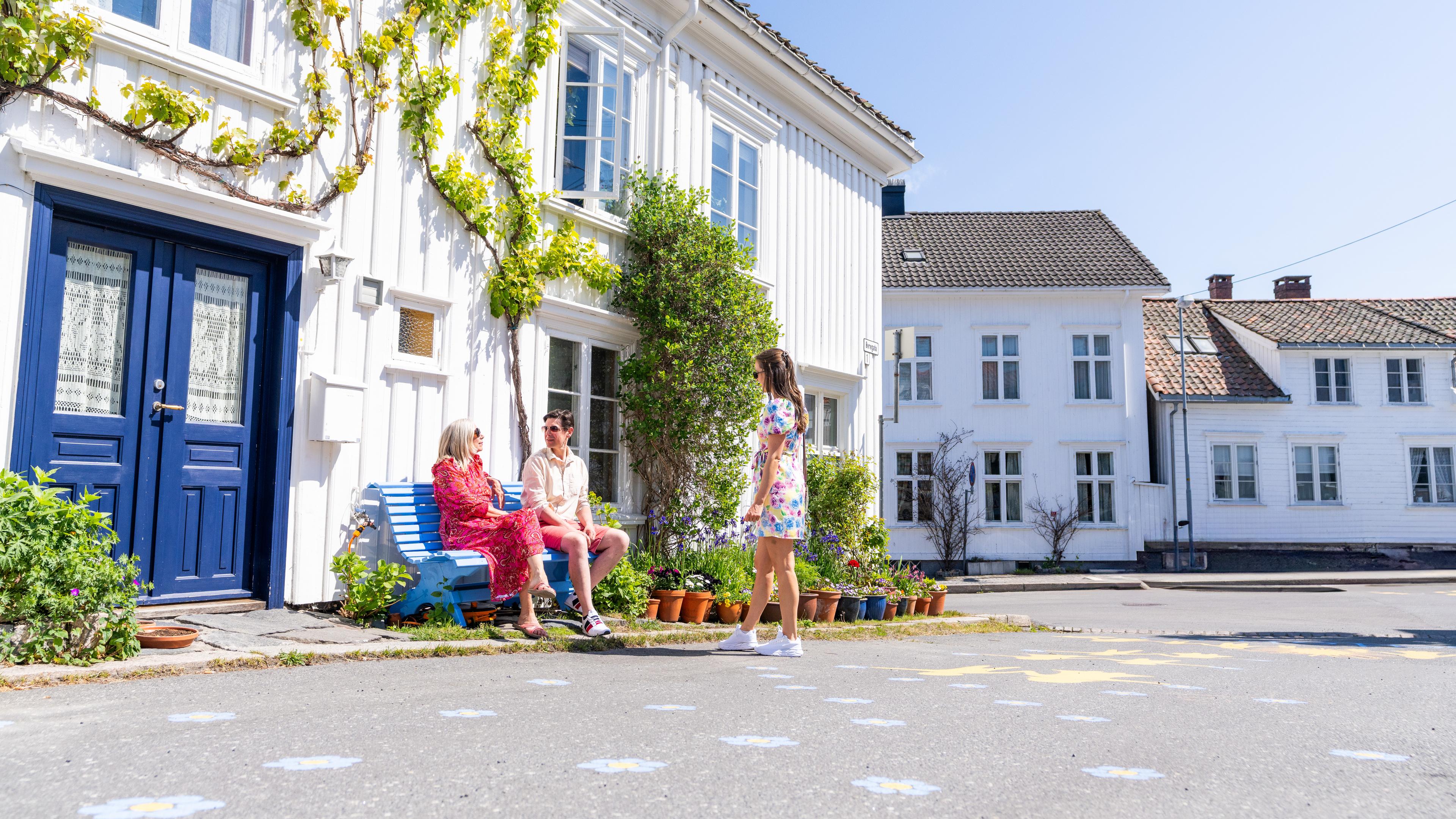 Three people sightseeing in a neighborhood in Risør, Southern Norway