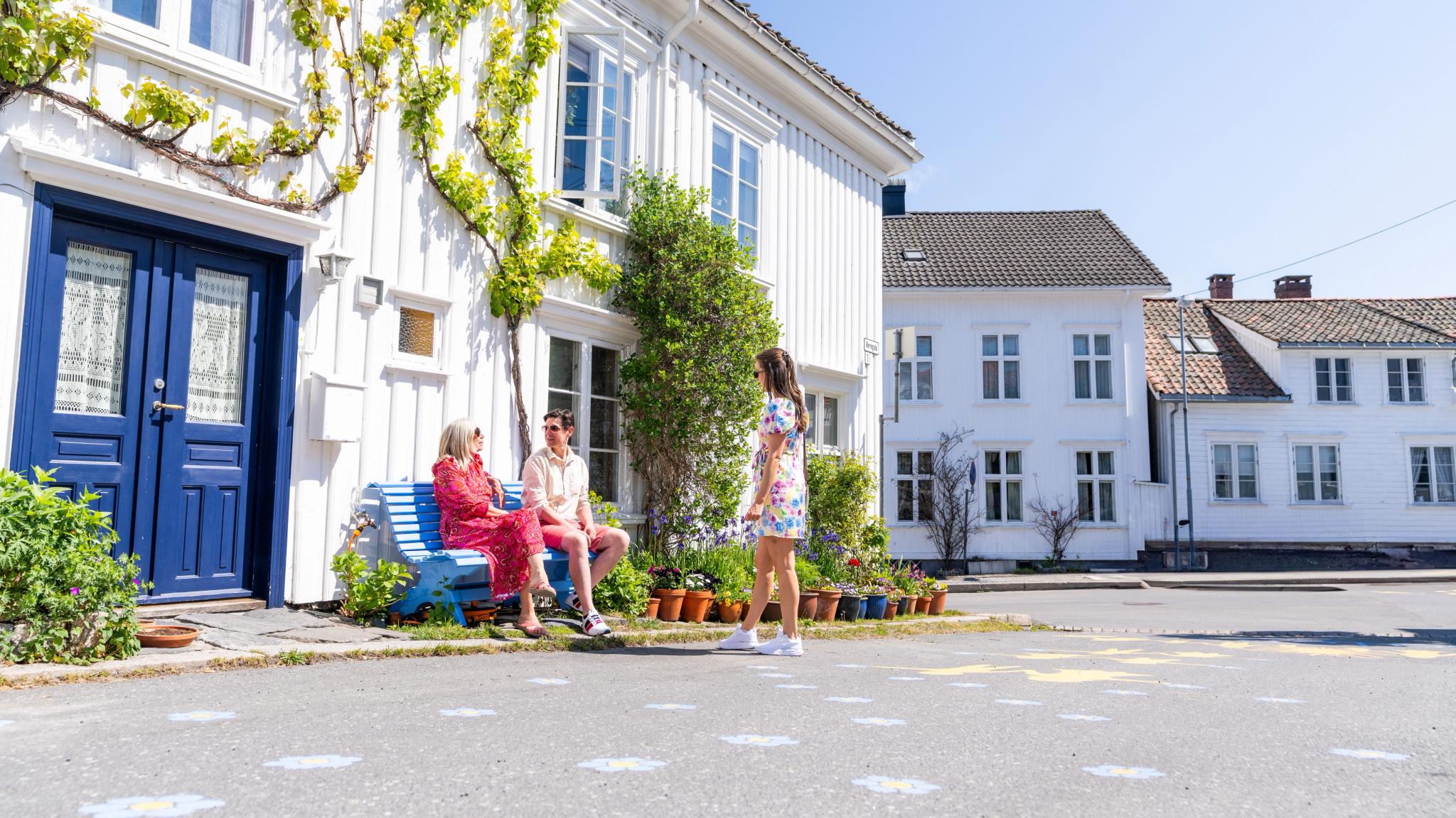 Three people sightseeing in a neighborhood in Risør, Southern Norway