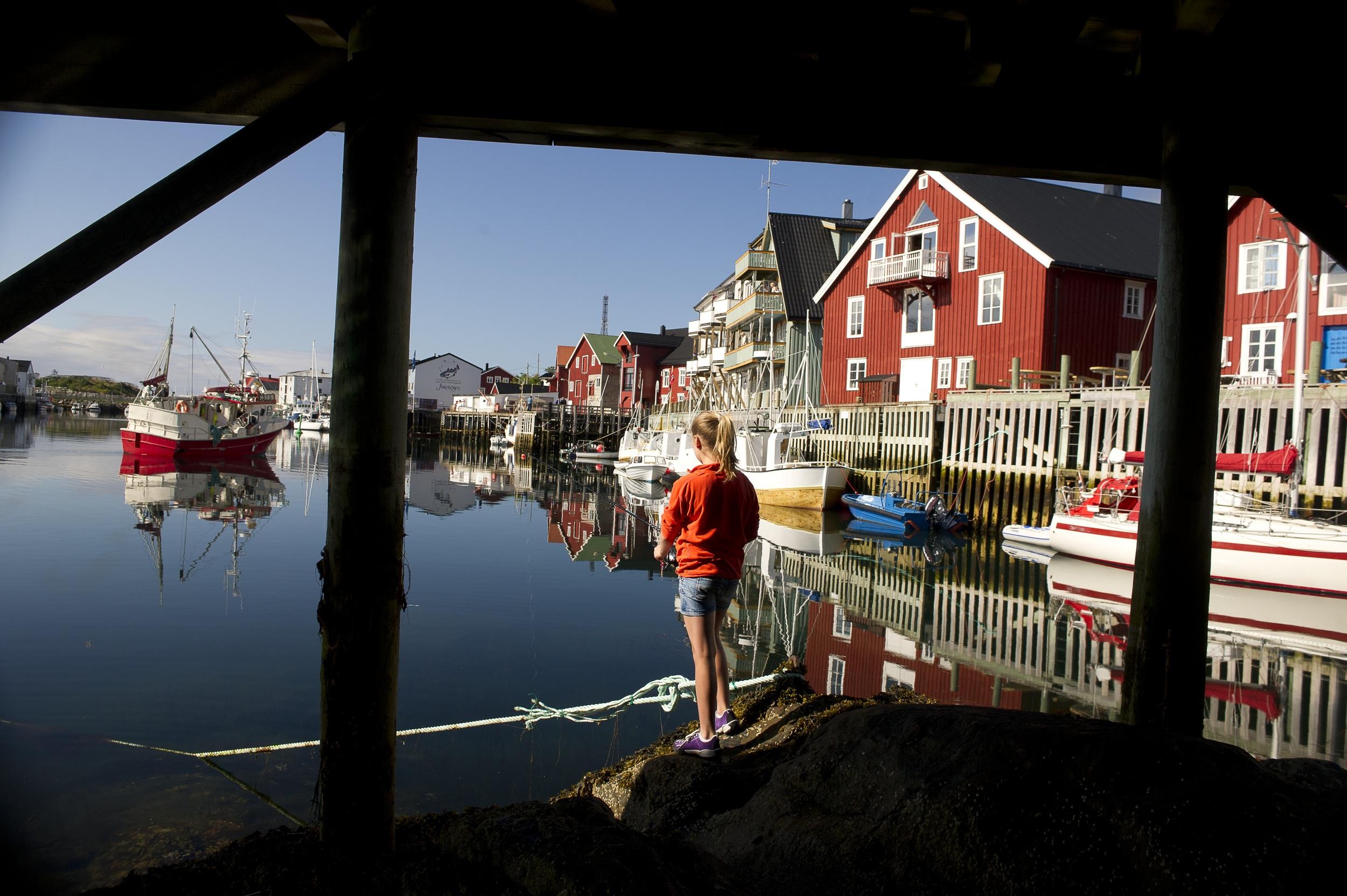 A girl is fishing a summer day in Henningsvær in Lofoten in Northern Norway
