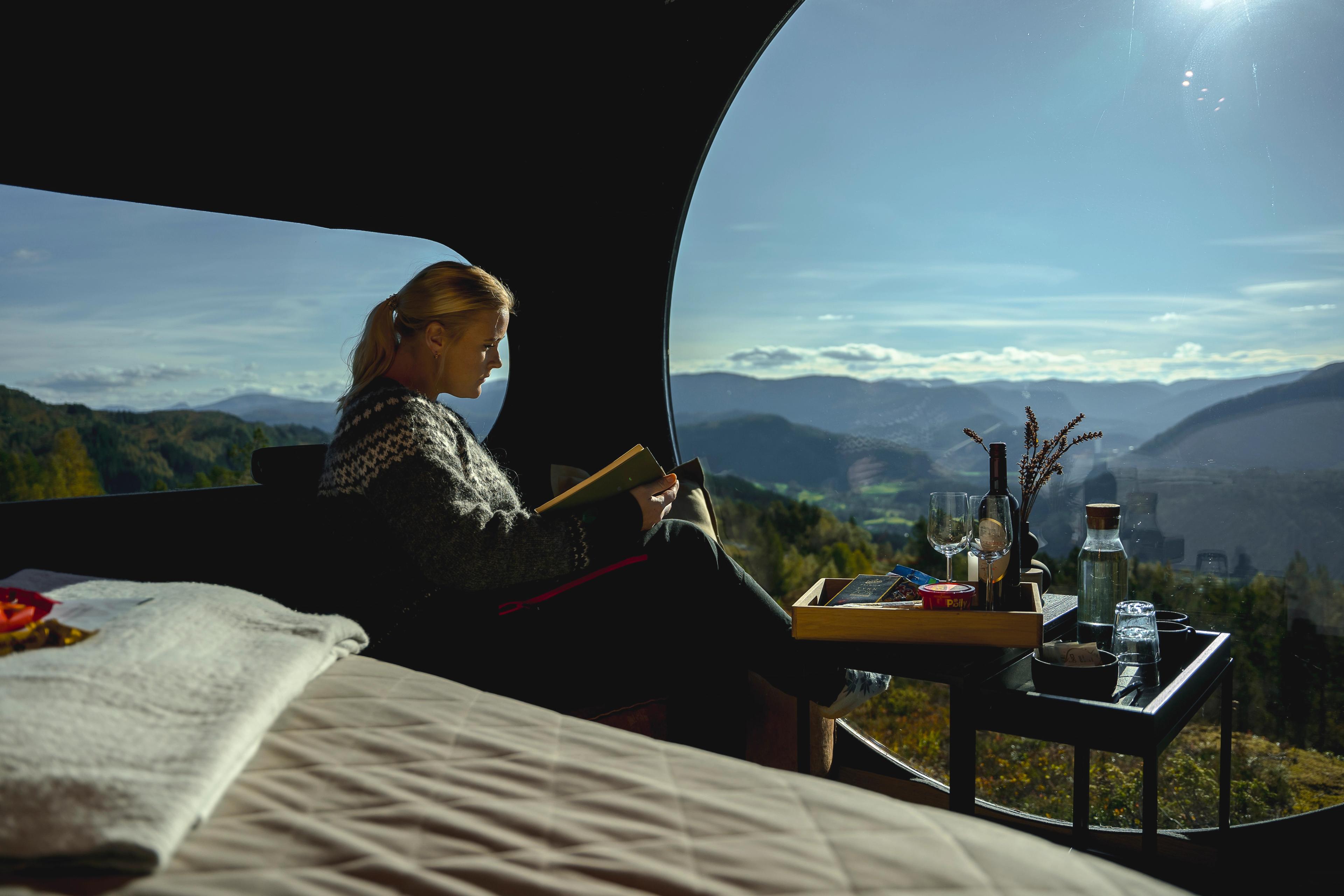 Woman reading a book inside Birdbox Langeland