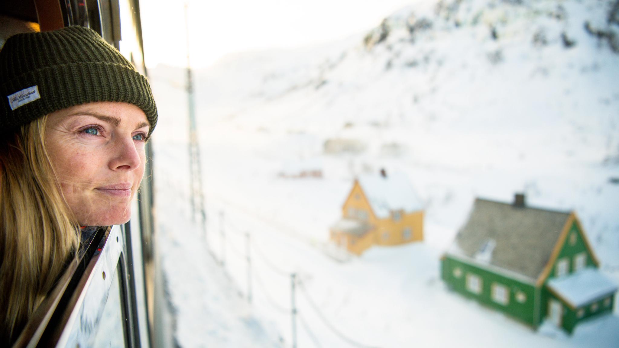 A woman looking out of the train along Flåmsbana