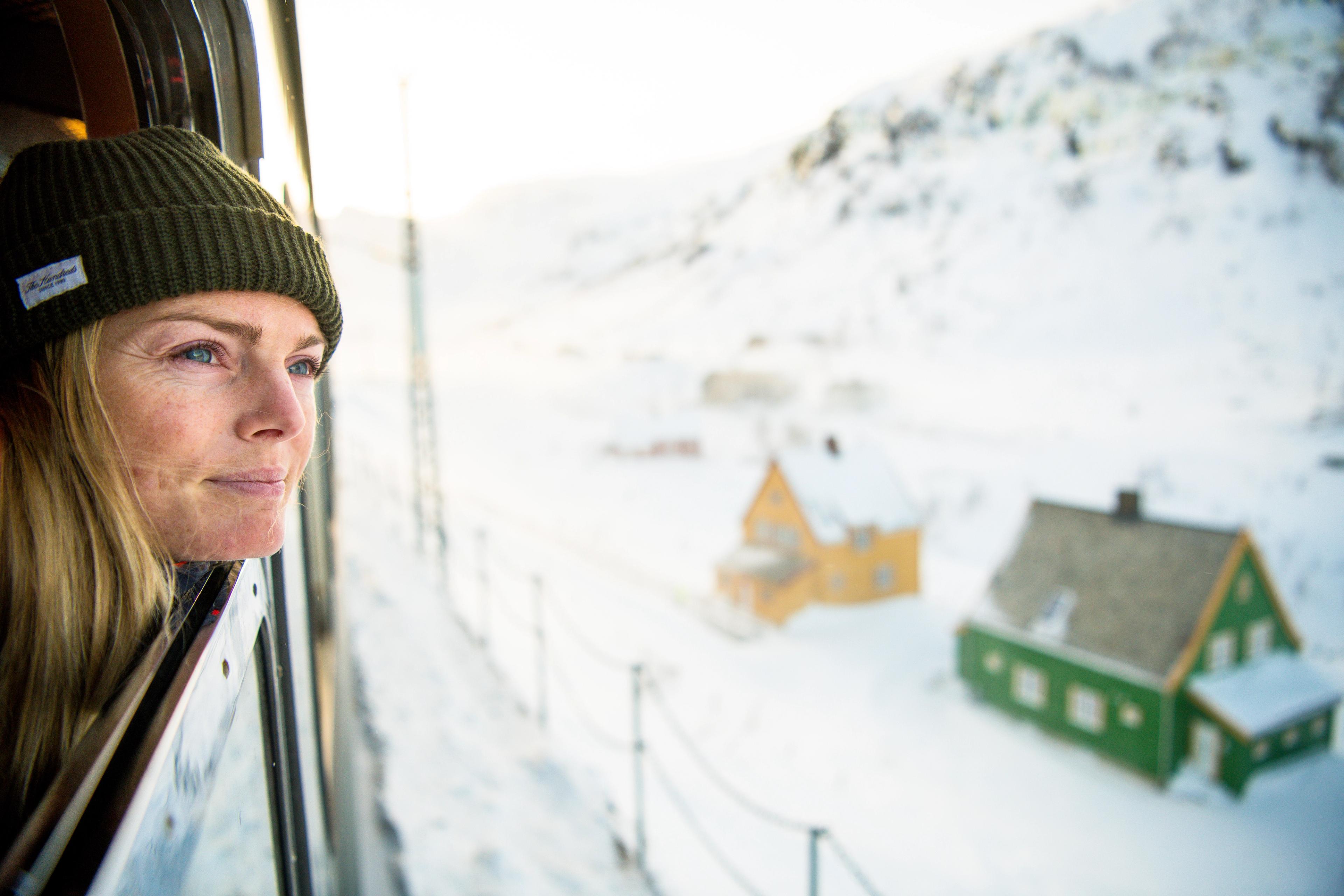 A woman looking out of the train along Flåmsbana