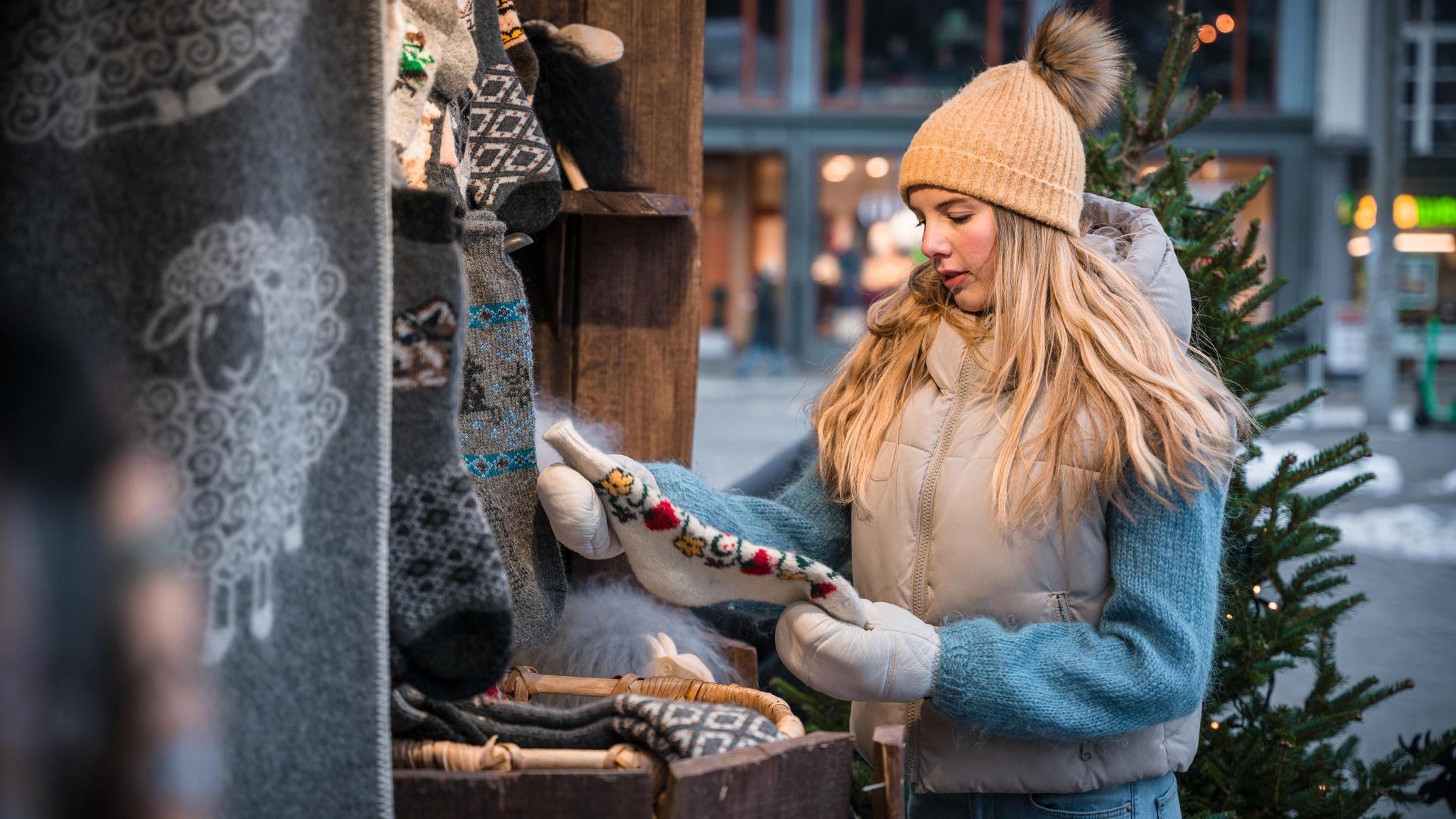 A girl shopping wool items at a Christmas market in Bergen, Fjord Norway