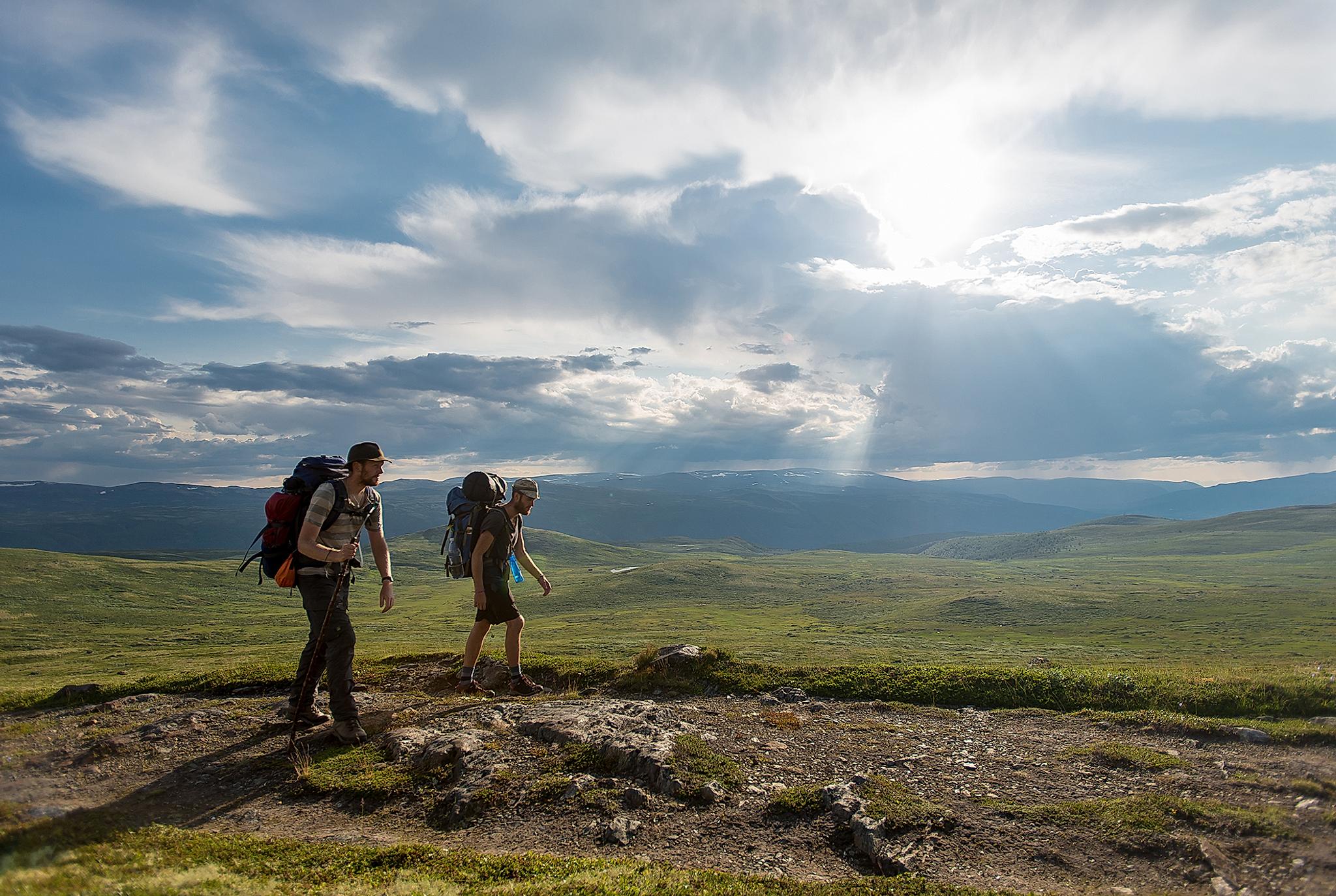 Two men wearing backpacks hiking the Gudbrandsdalen path, the pilgrim trail St. Olav Ways to Trondheim, across Dovrefjell in Eastern Norway
