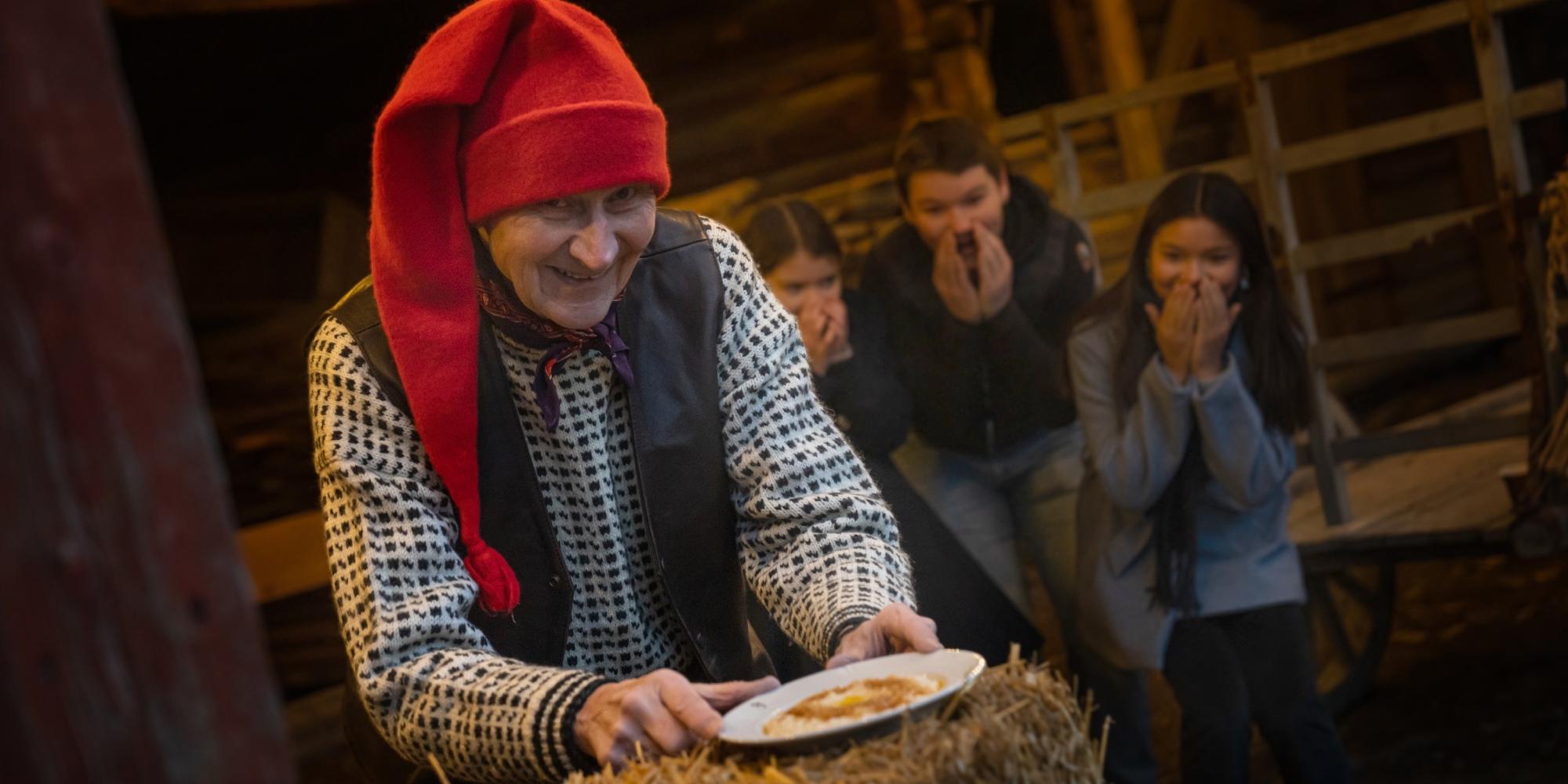 The Norwegian Santa is getting a hold of the porridge, while children is excited in the background at Bygdøy, Eastern Norway