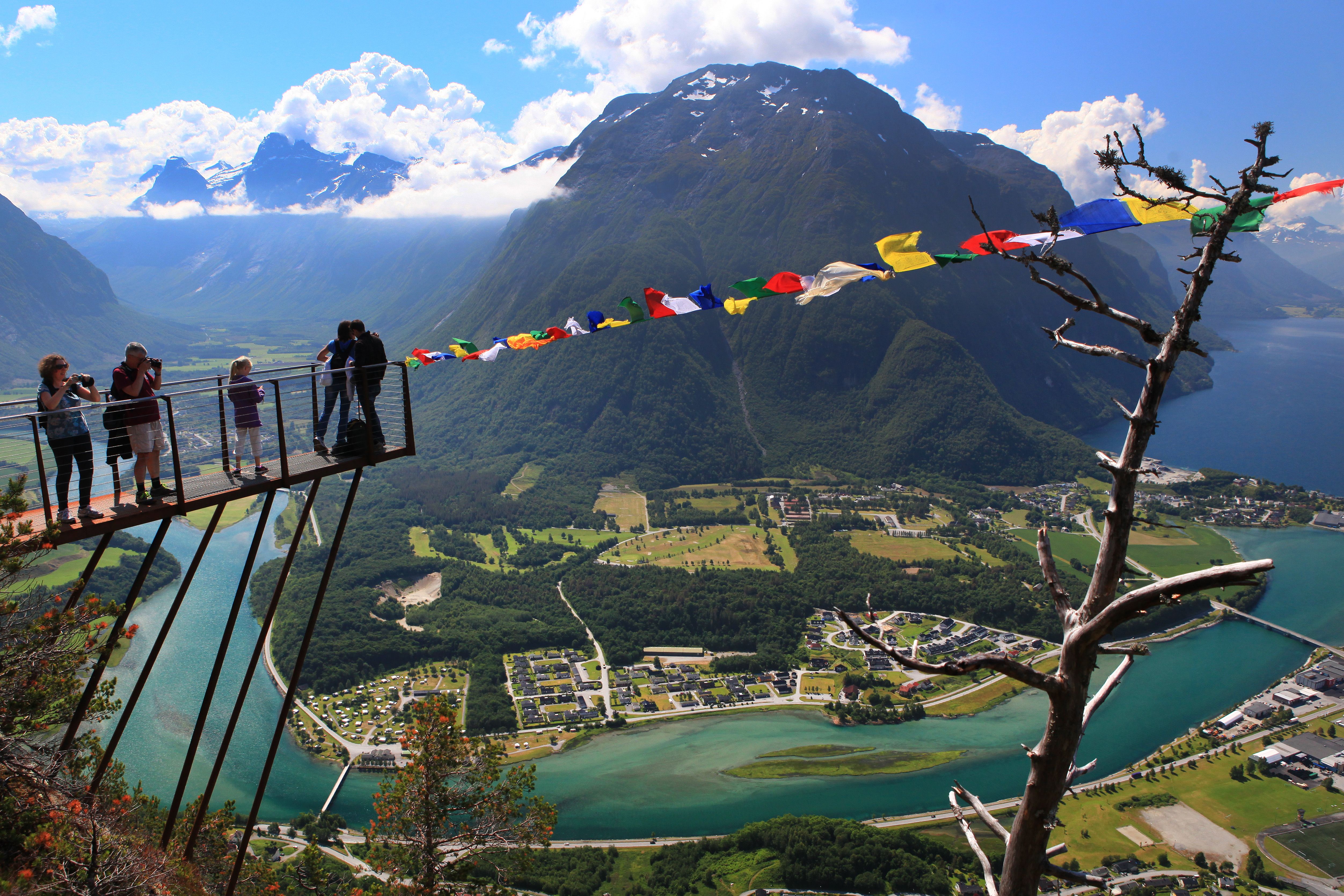 A group of people standing at the tip of the Rampestreken viewpoint looking at the view of Åndalsnes in Northwest, Fjord Norway.