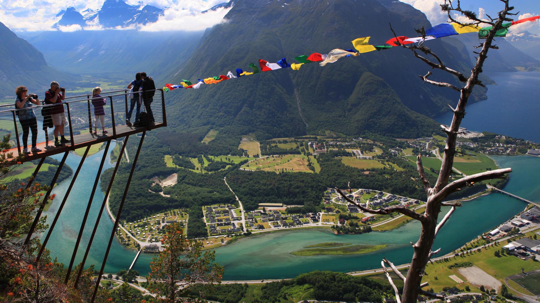 A group of people standing at the tip of the Rampestreken viewpoint looking at the view of Åndalsnes in Northwest, Fjord Norway.
