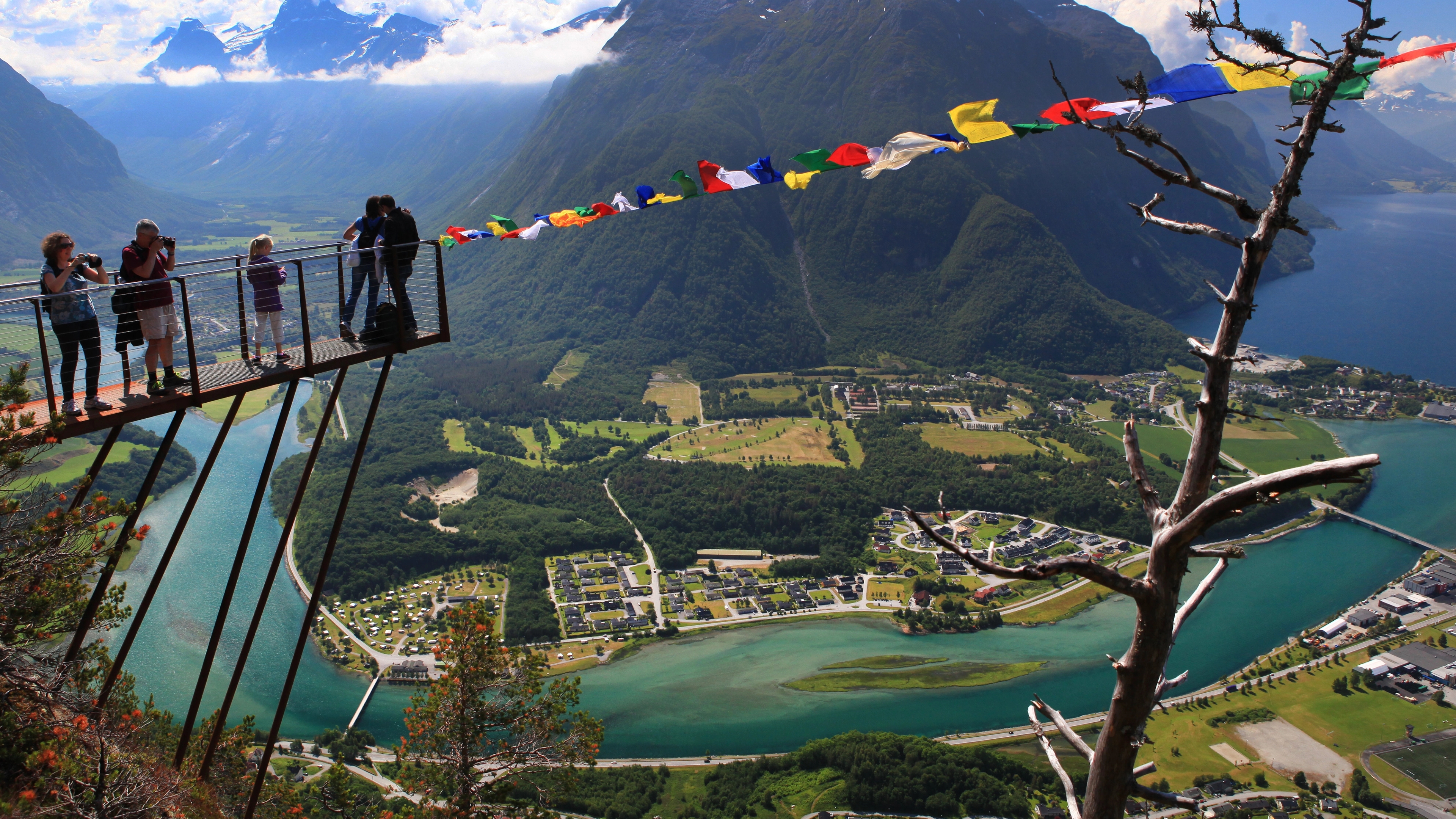 A group of people standing at the tip of the Rampestreken viewpoint looking at the view of Åndalsnes in Northwest, Fjord Norway.