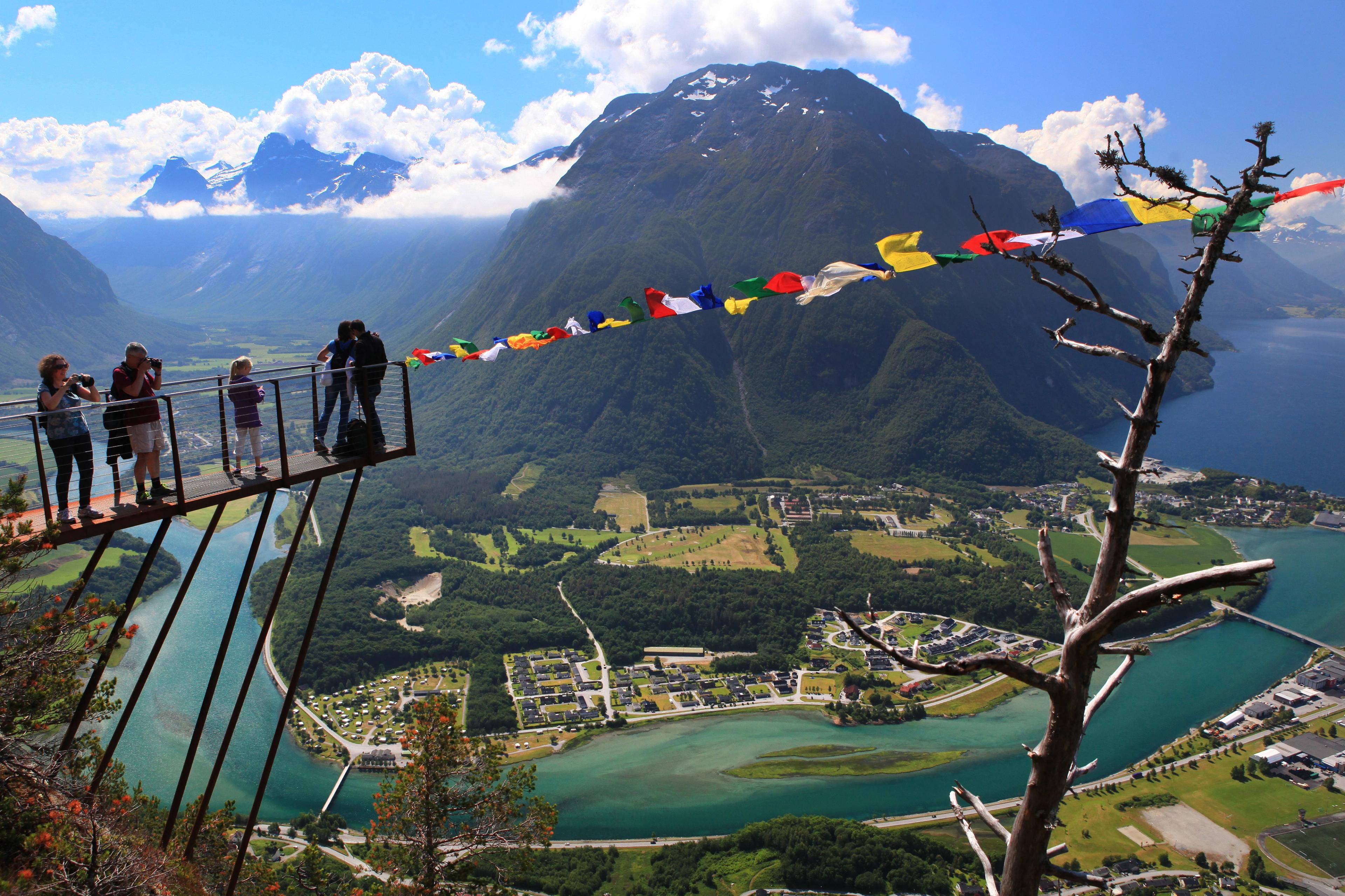 A group of people standing at the tip of the Rampestreken viewpoint looking at the view of Åndalsnes in Northwest, Fjord Norway.