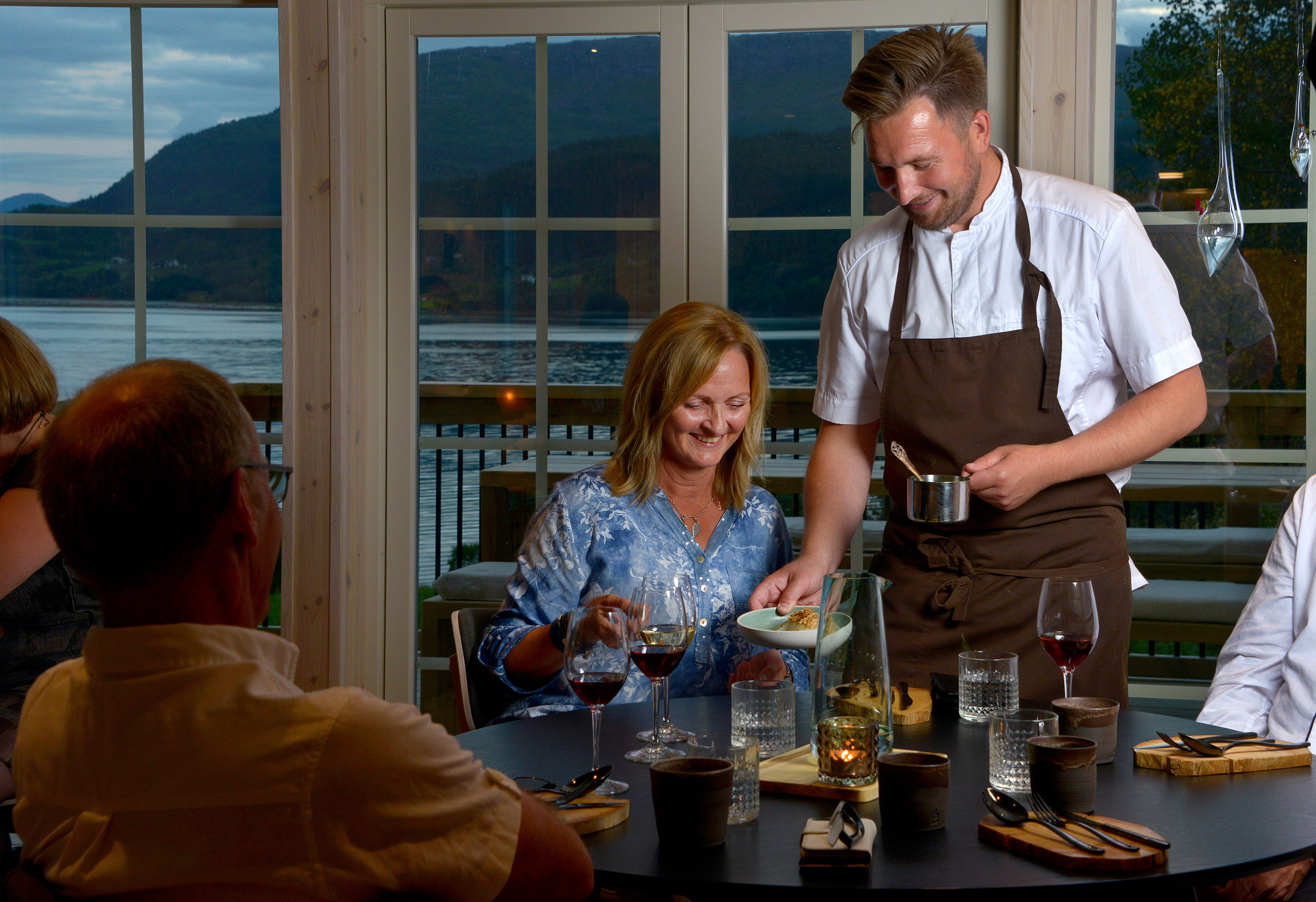 En servitør serverer mat på restauranten Fra Marius på Utskarpen på Helgeland i Nord-Norge