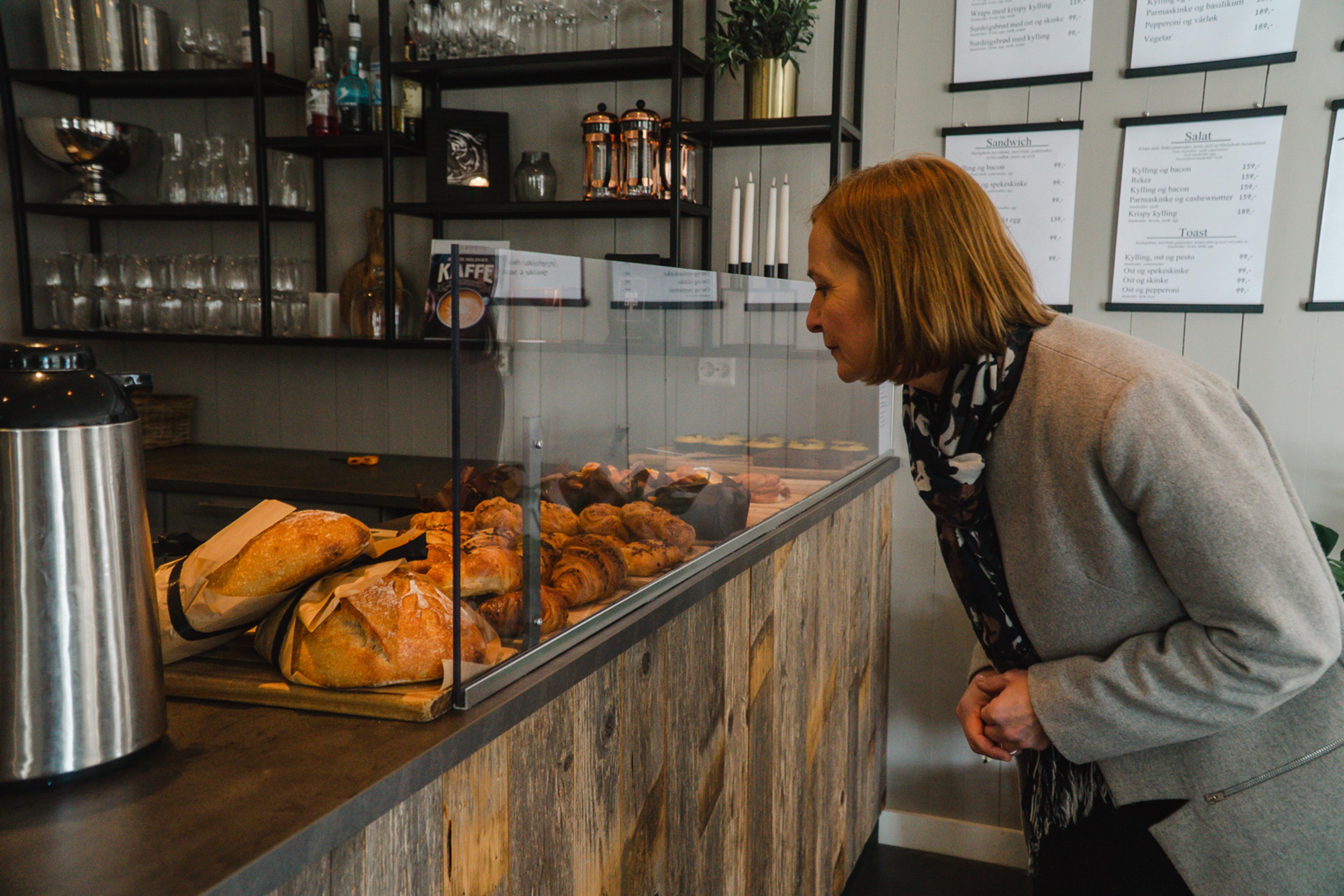 A woman looking at buns and breads at Herlighed café in Grimstad, Southern Norway.