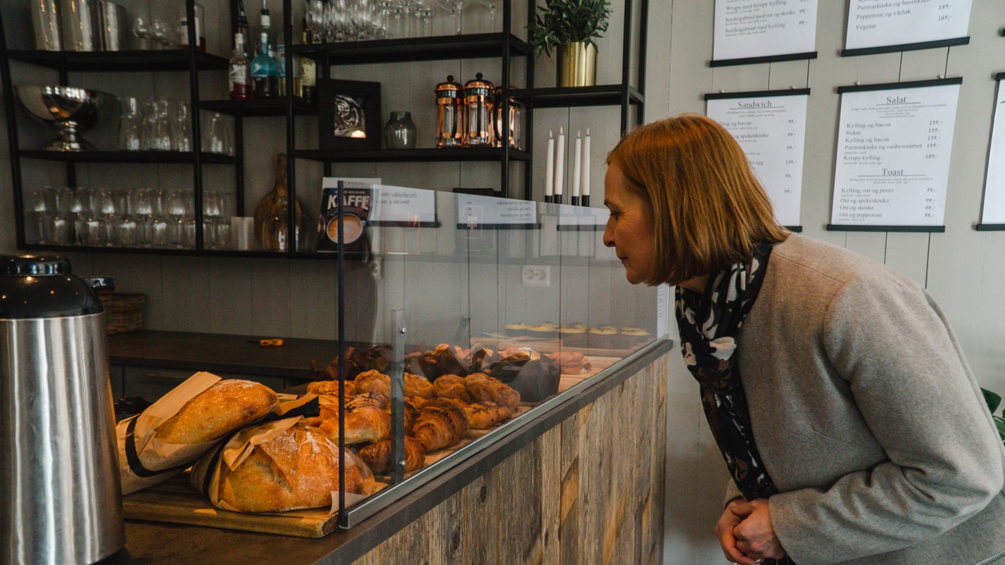 A woman looking at buns and breads at Herlighed café in Grimstad, Southern Norway.