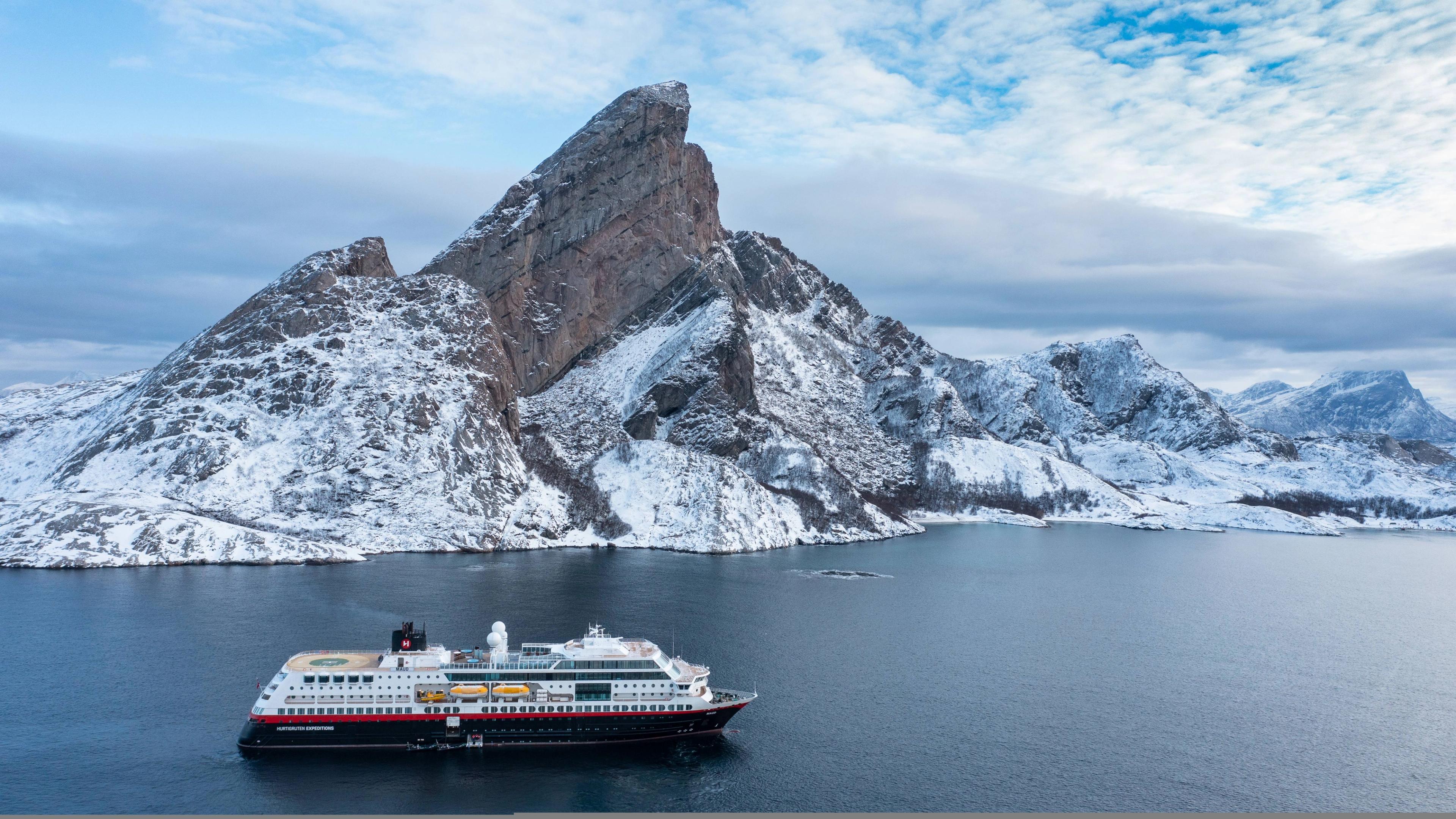 Hurtigruten sailing by a mountain in Northern Norway.