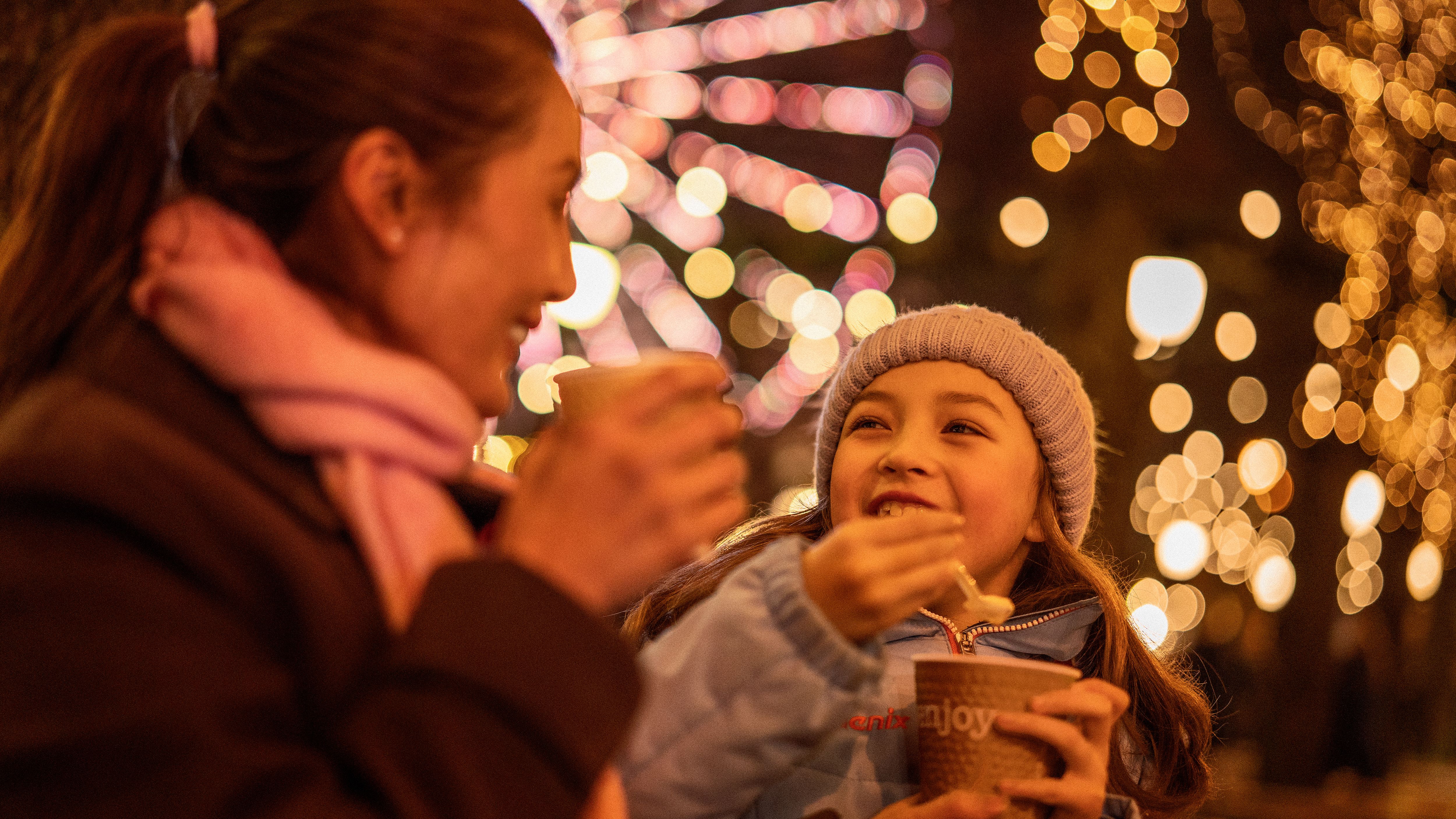 En jente og en kvinne koser seg med grøt på julemarkedet i Oslo.