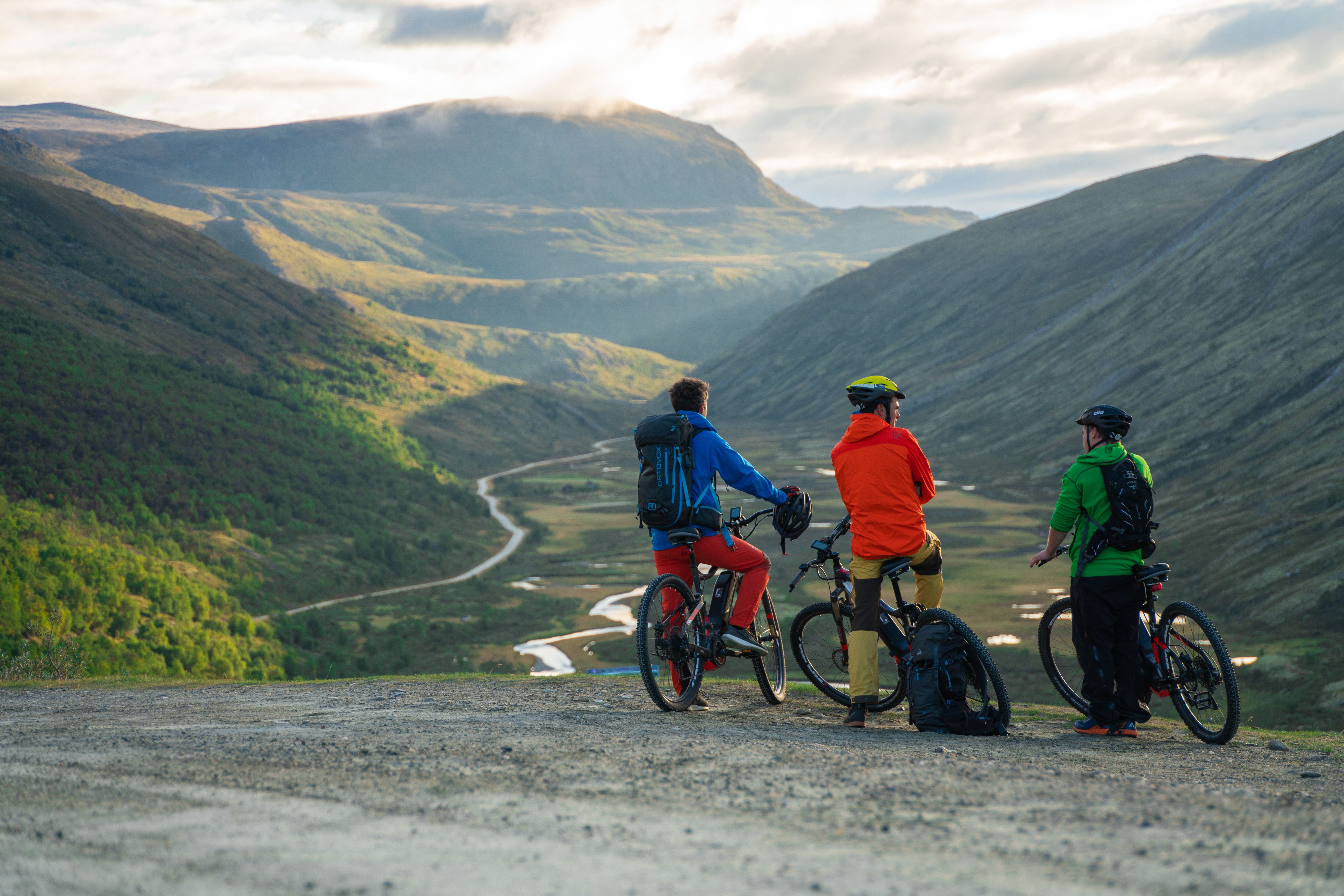 Three people on bikes looking at a valley below