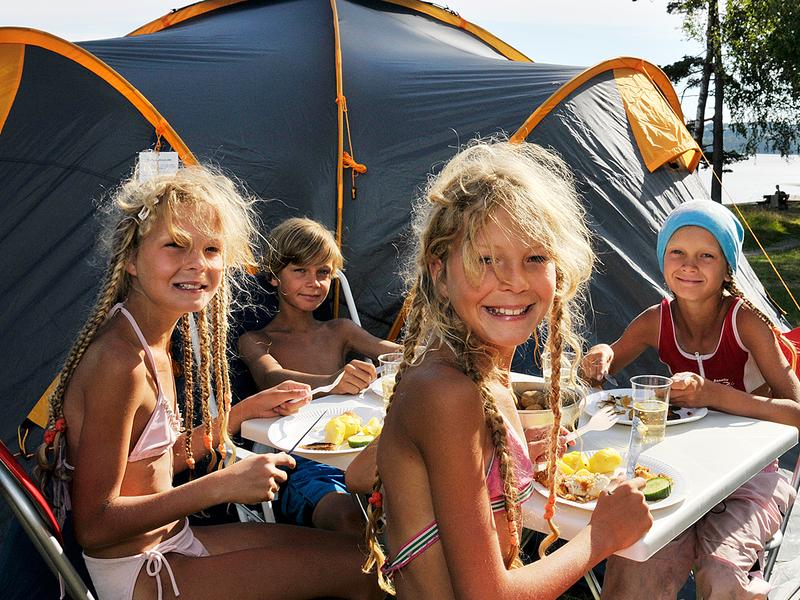 Children eating outside a camping tent on Hamre famliecamping in Kristiansand, Southern Norway