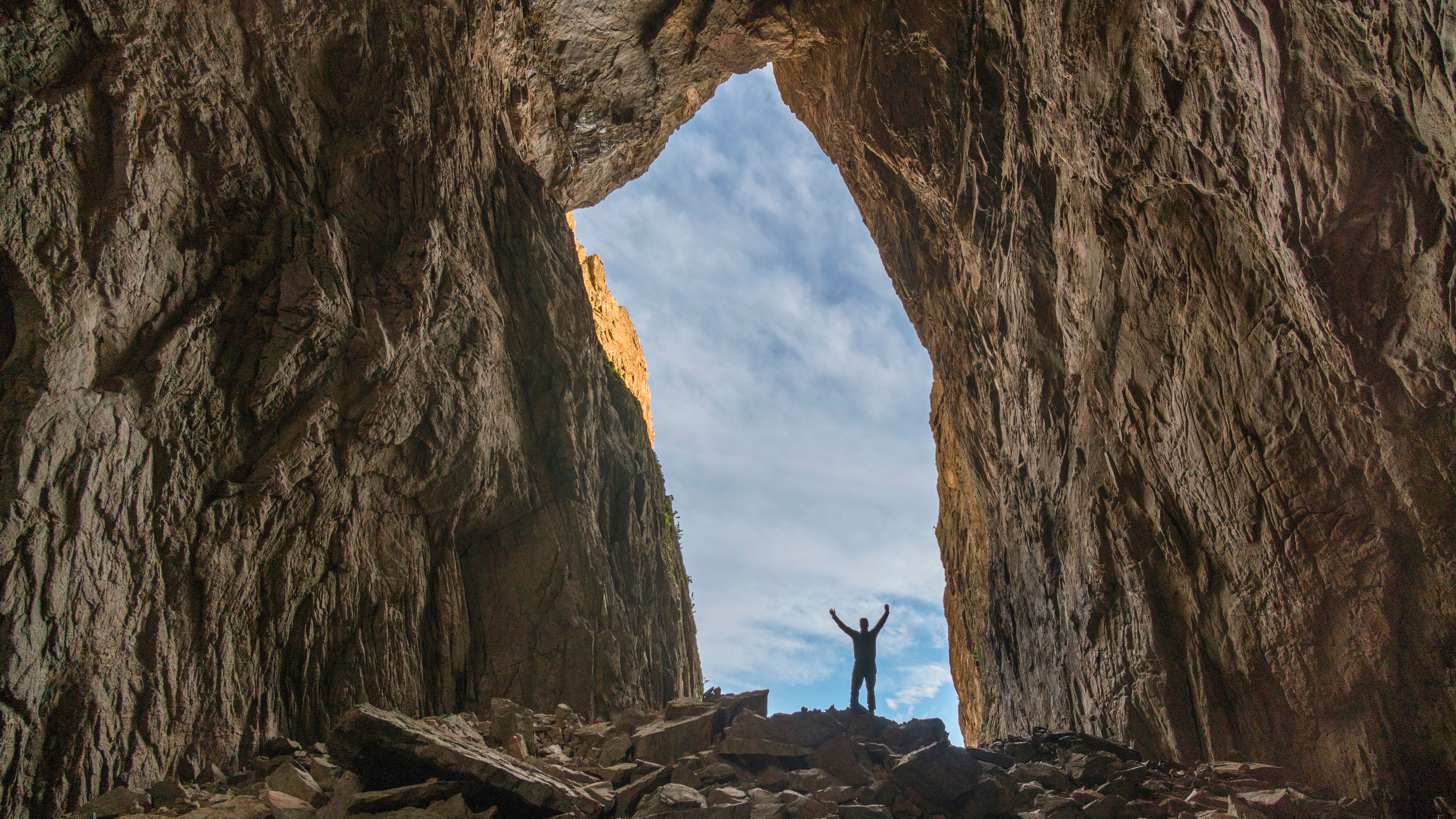 A person standing in the iconic hole in the Torghatten mountain in Brønnøy, Northern Norway.