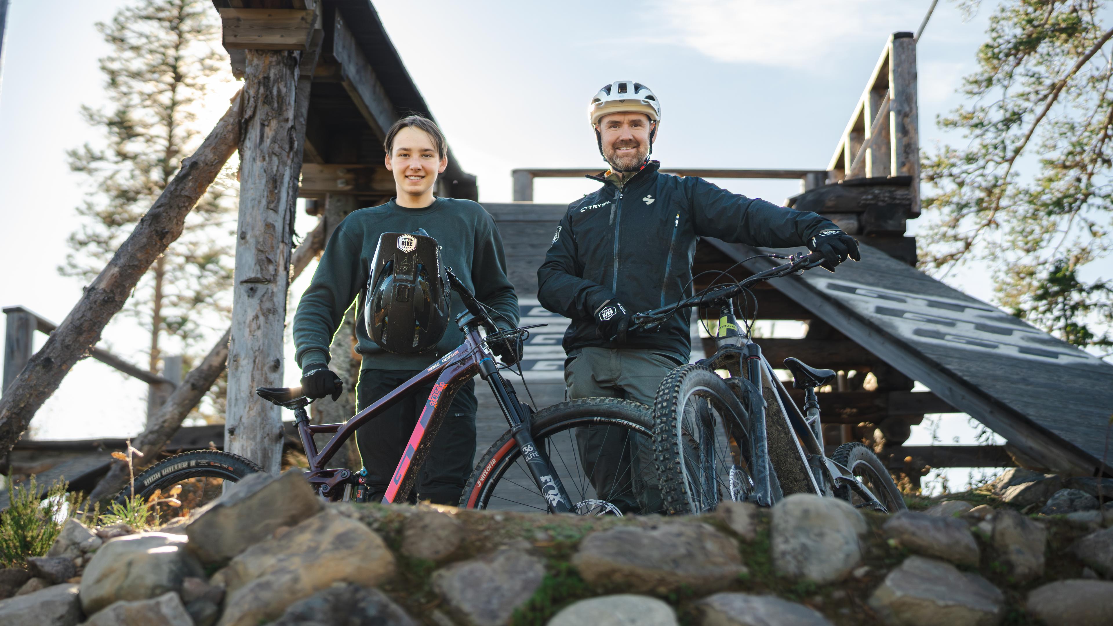 Sondre and his father Olve with their mountain bikes in front of a jump.