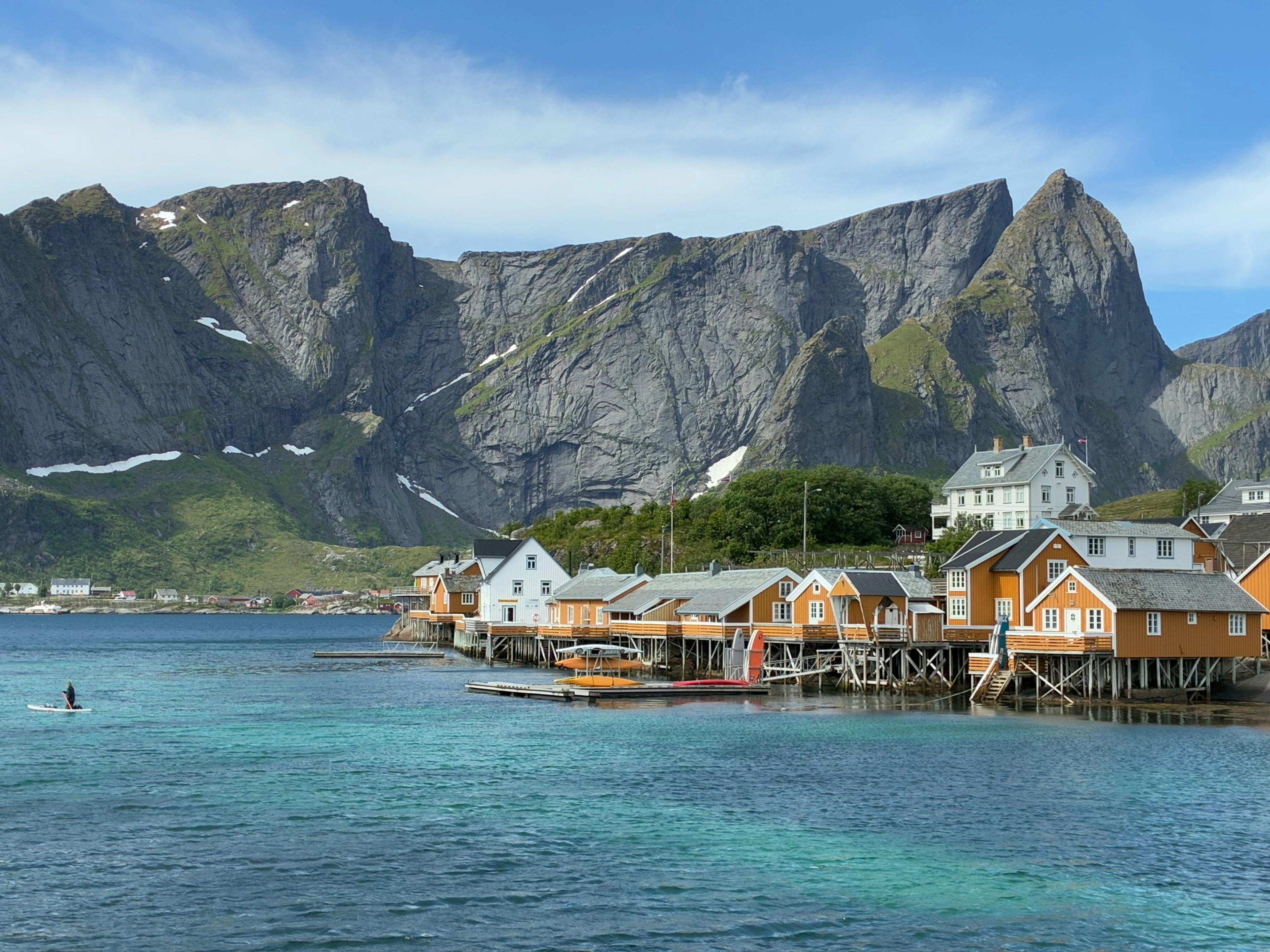 Norwegian fishing village on stilts over water with mountains in the background