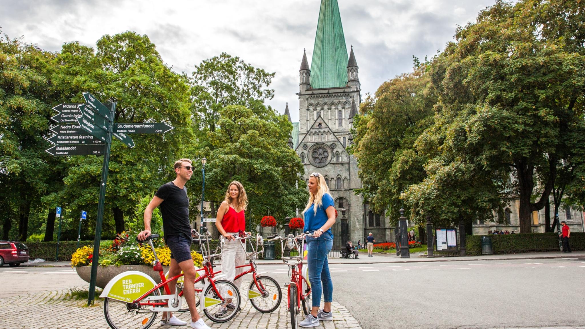 Tre personer med cyklar på besök i Trondheim, Norge