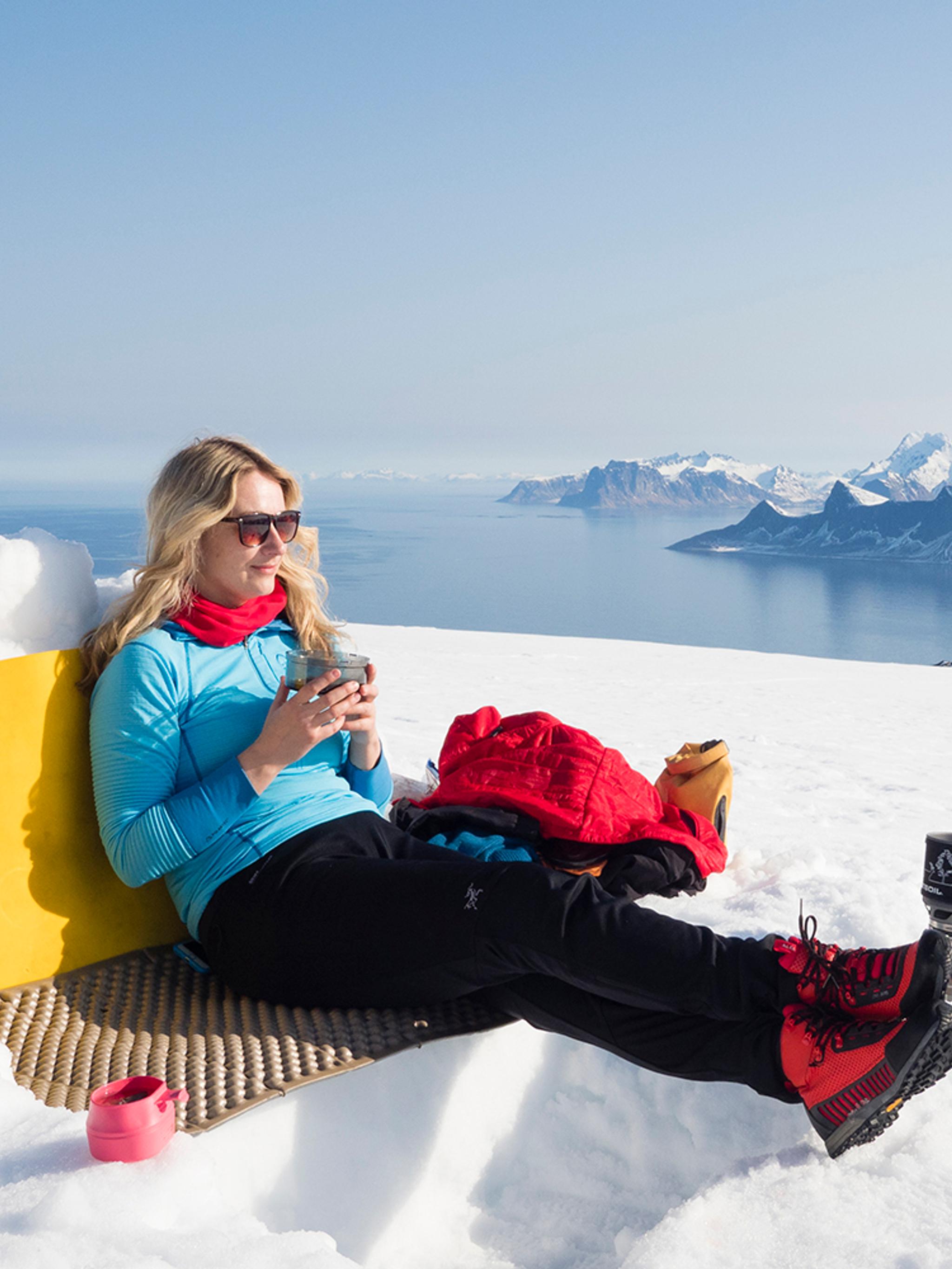 Woman enjoying a break on a winter hike to Mount Ryten in Lofoten, Northern Norway
