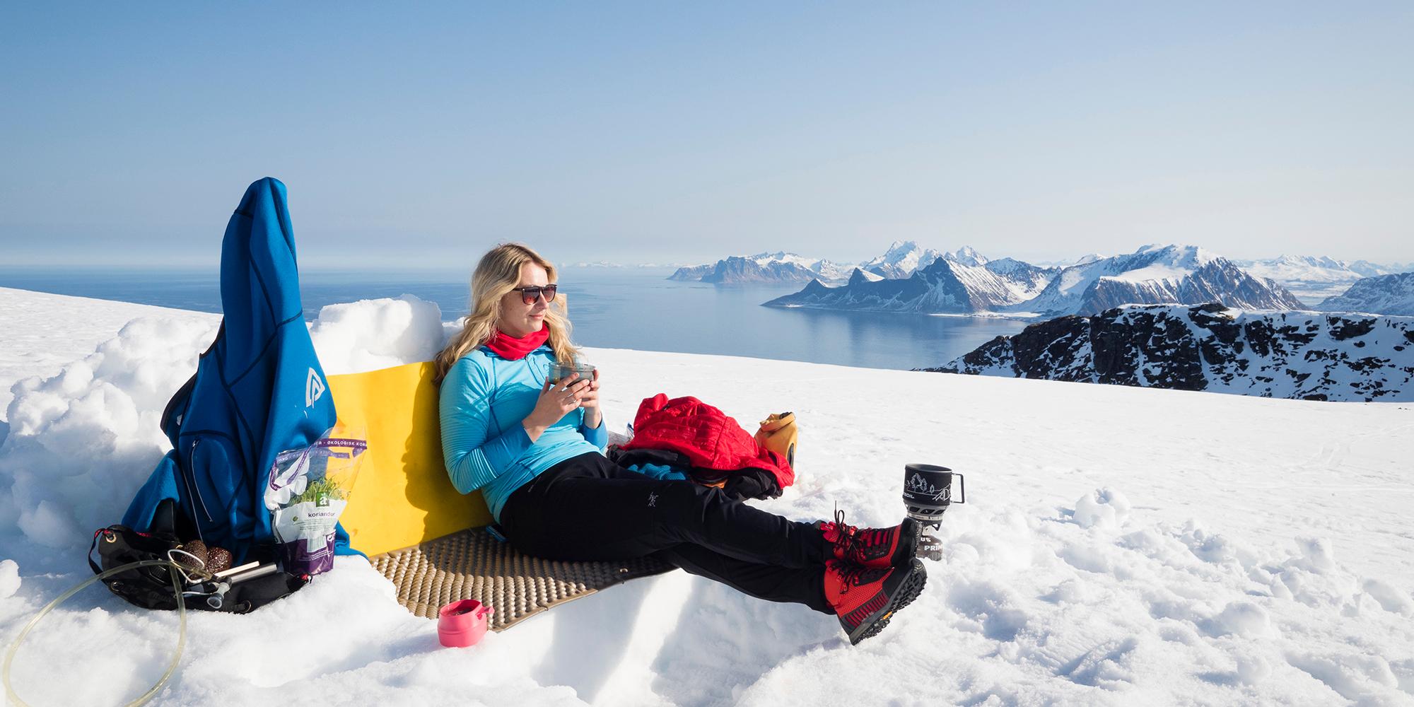 Woman enjoying a break on a winter hike to Mount Ryten in Lofoten, Northern Norway