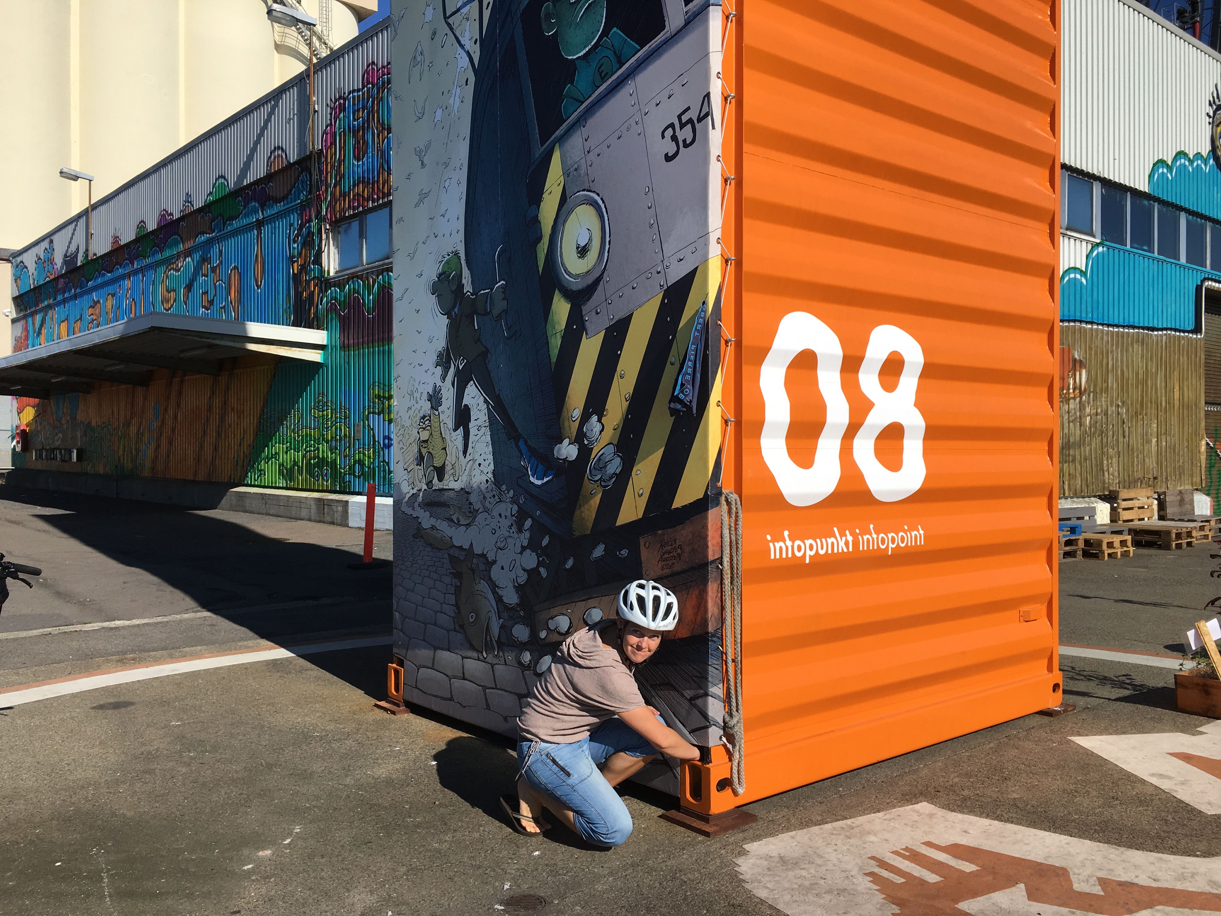 A woman while geocaching at an infopoint at a container with street art in Oslo, Norway