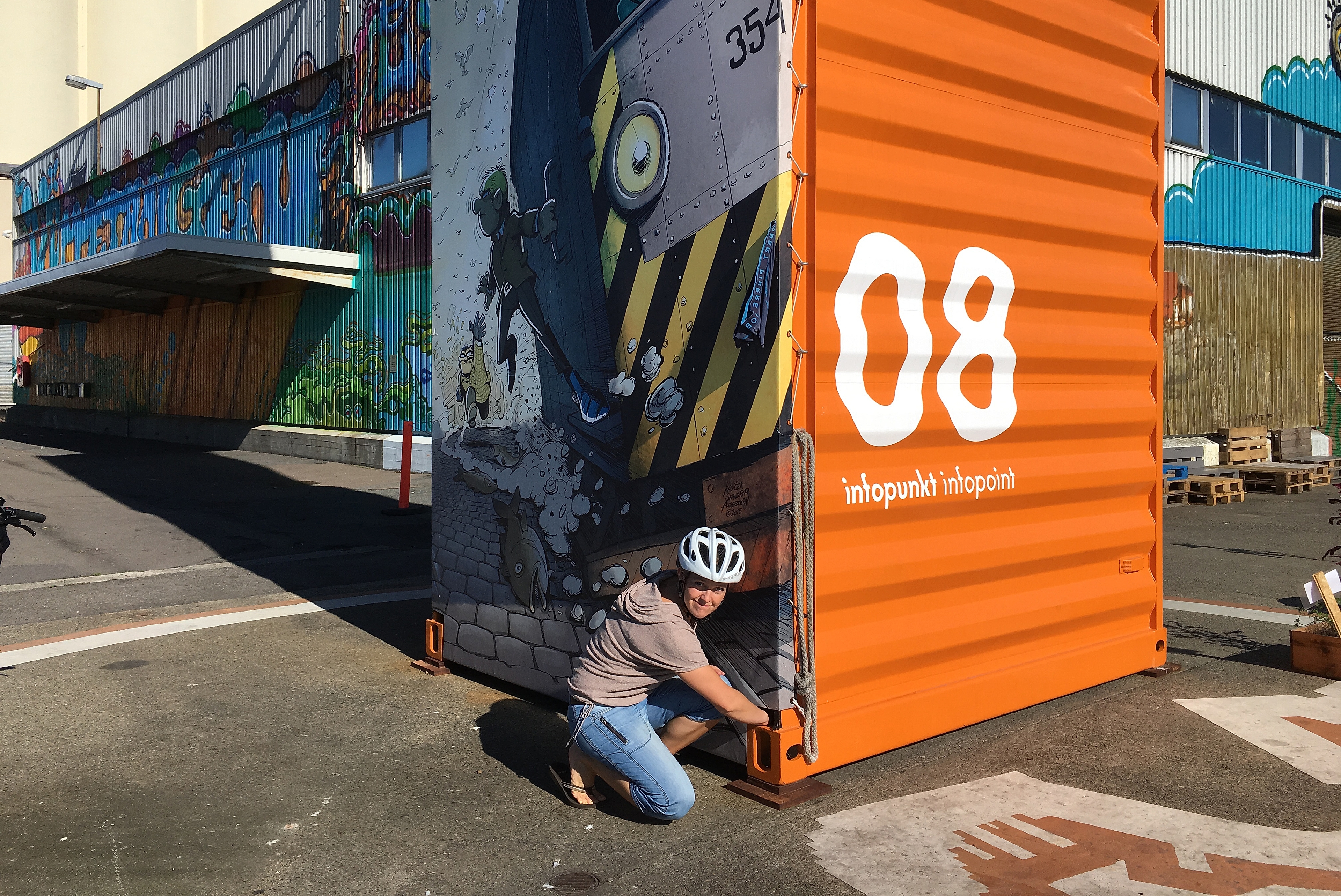 A woman while geocaching at an infopoint at a container with street art in Oslo, Norway