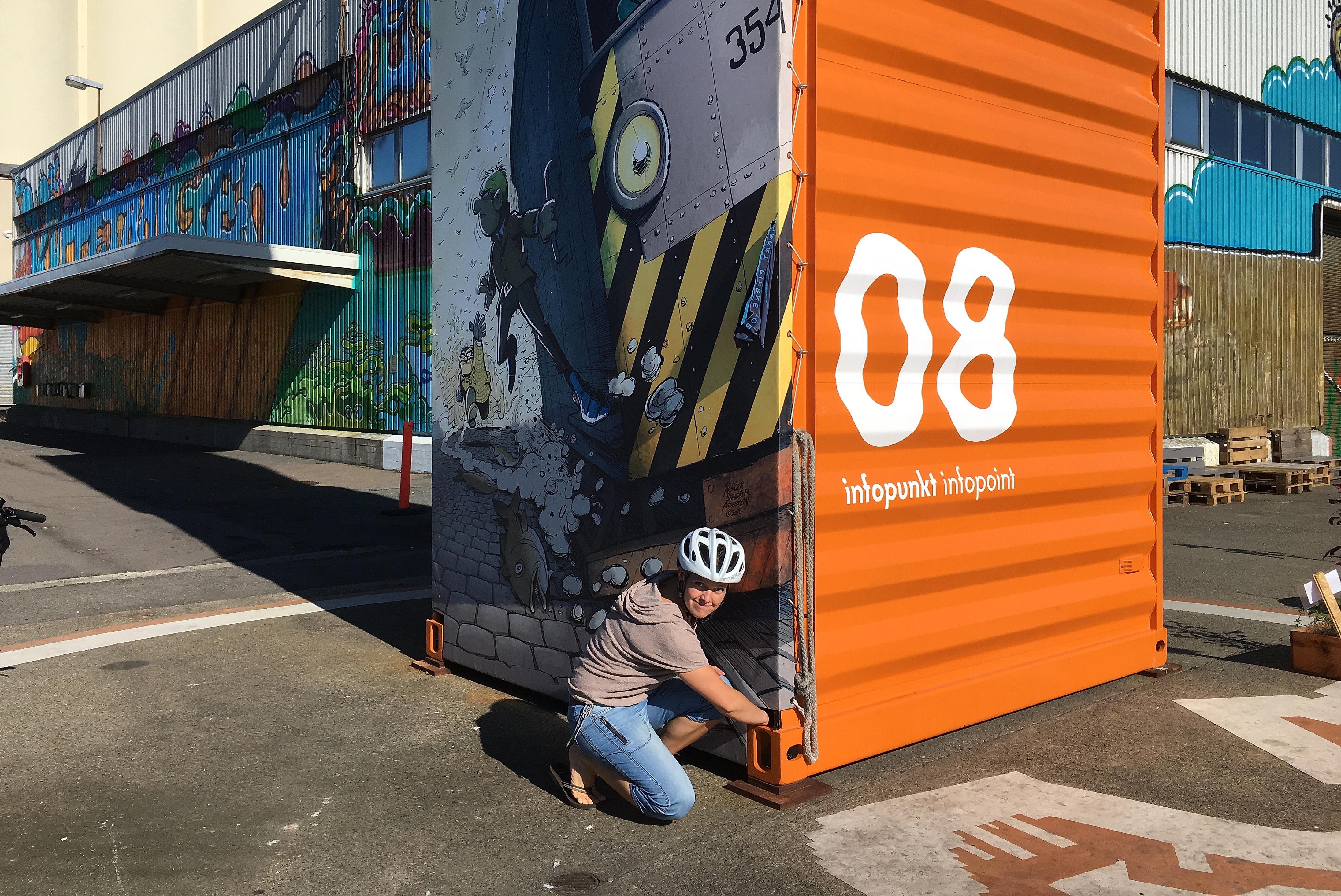 A woman while geocaching at an infopoint at a container with street art in Oslo, Norway