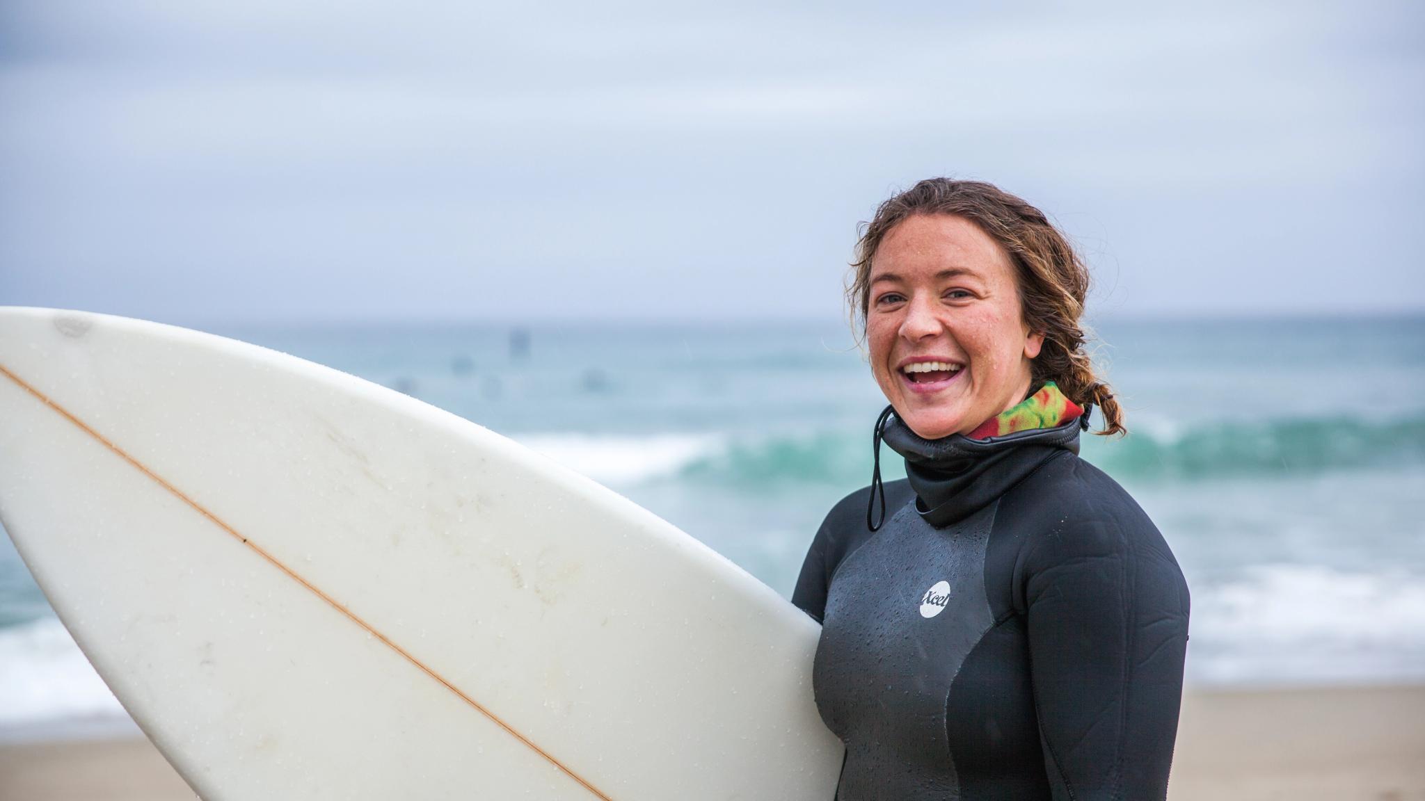 En dame holder et surfebrett på Solstranden i Stavanger på Vestlandet