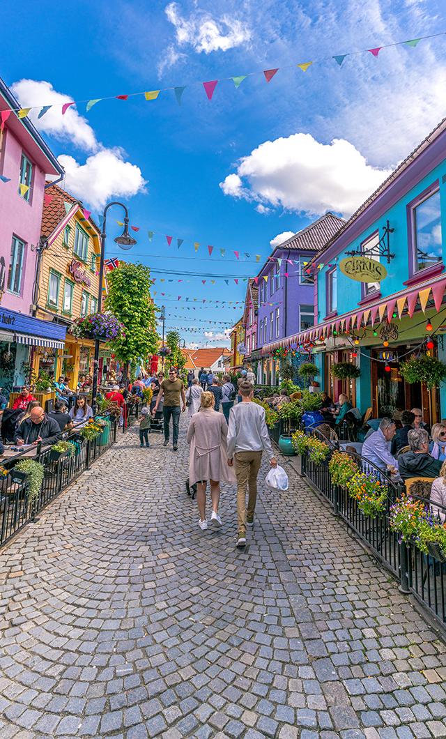 Two people walking down the colourful street Øvre Holmegate in Stavanger in Fjord Norway