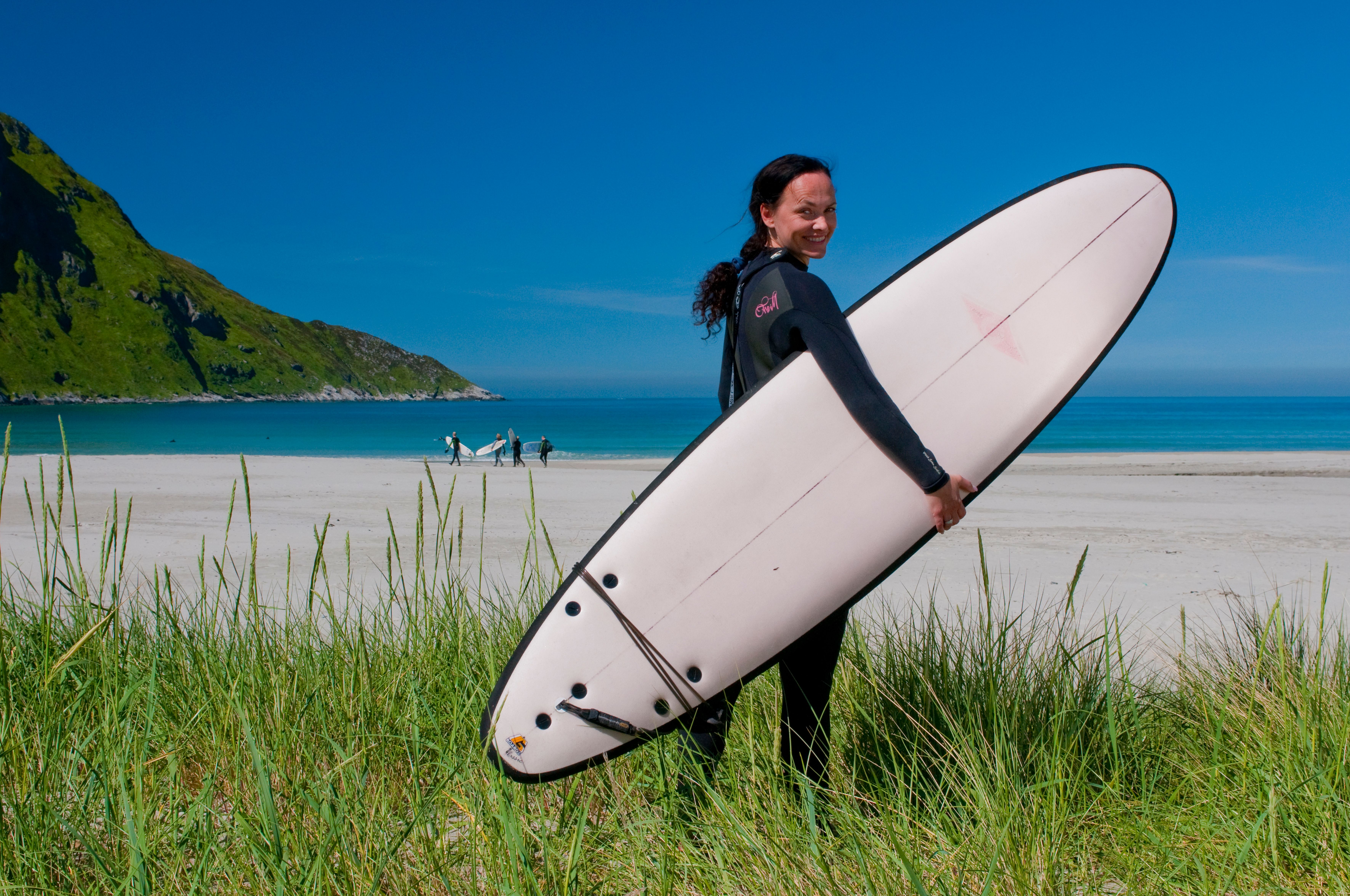 A woman with a surfboard at the beach at Hoddevik in Fjord Norway