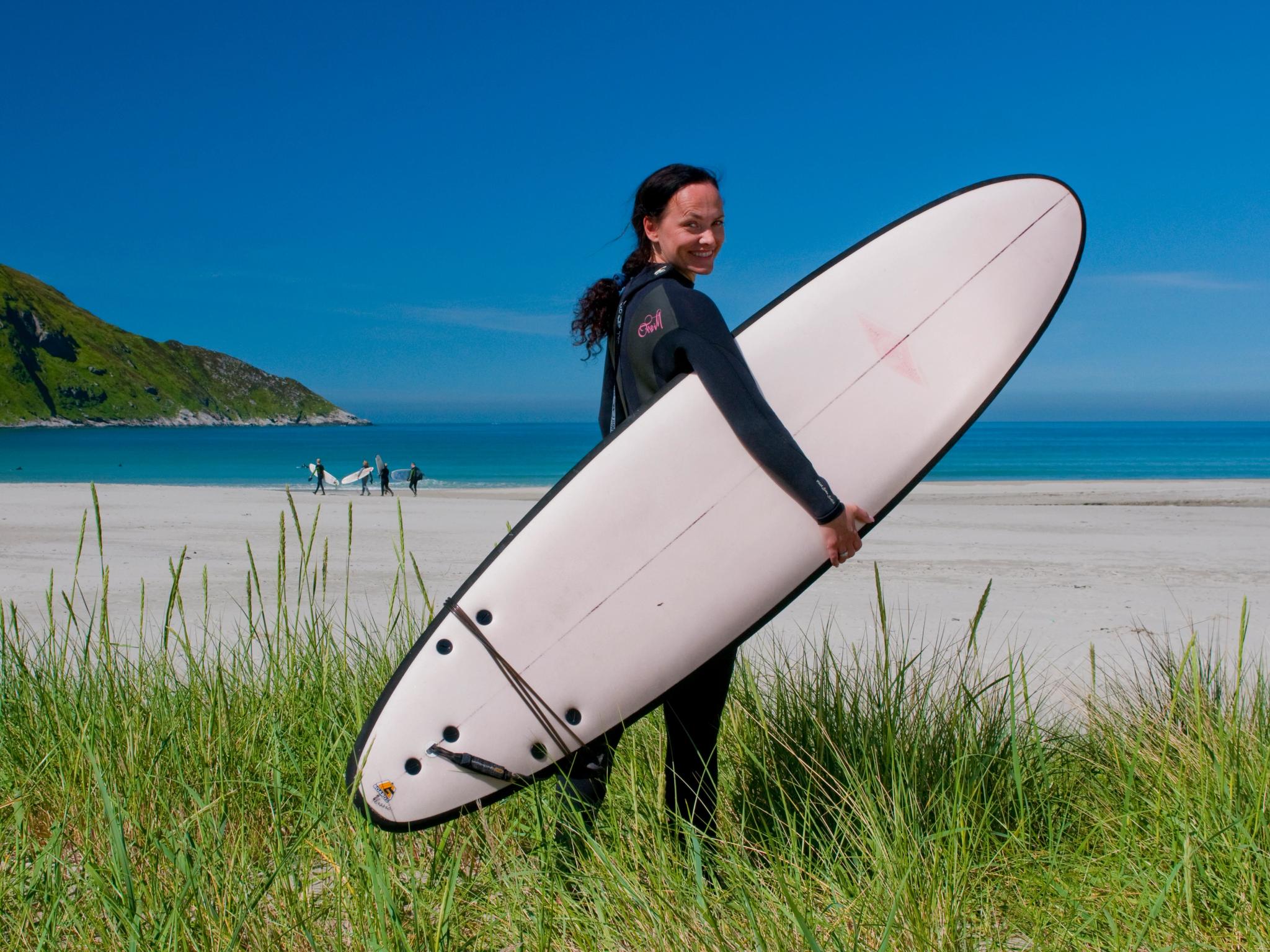 A woman with a surfboard at the beach at Hoddevik in Fjord Norway