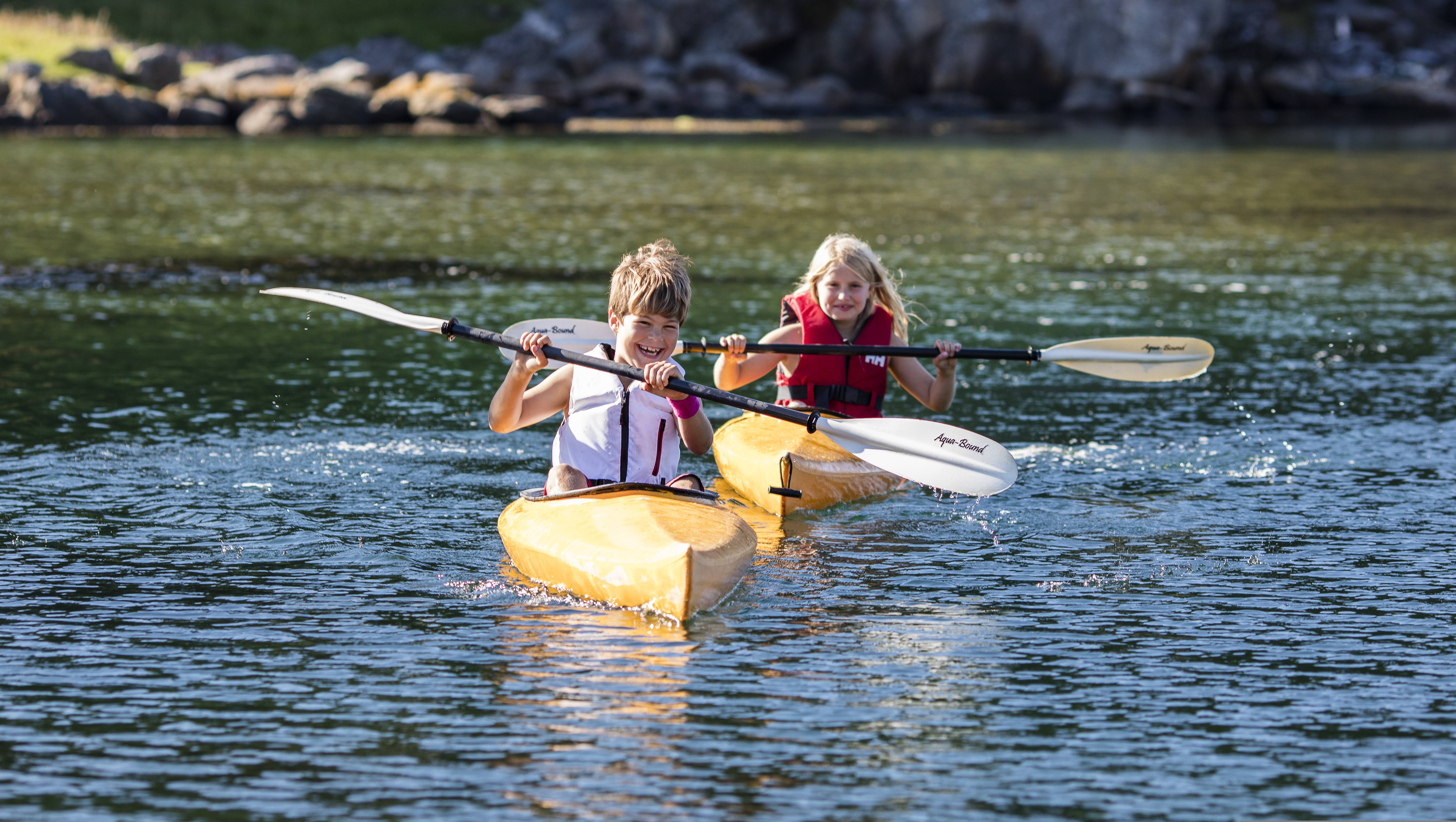 Två barn paddlar i vattnet vid ön Hidra utanför Flekkefjord i regionen Sørlandet (södra Norge)