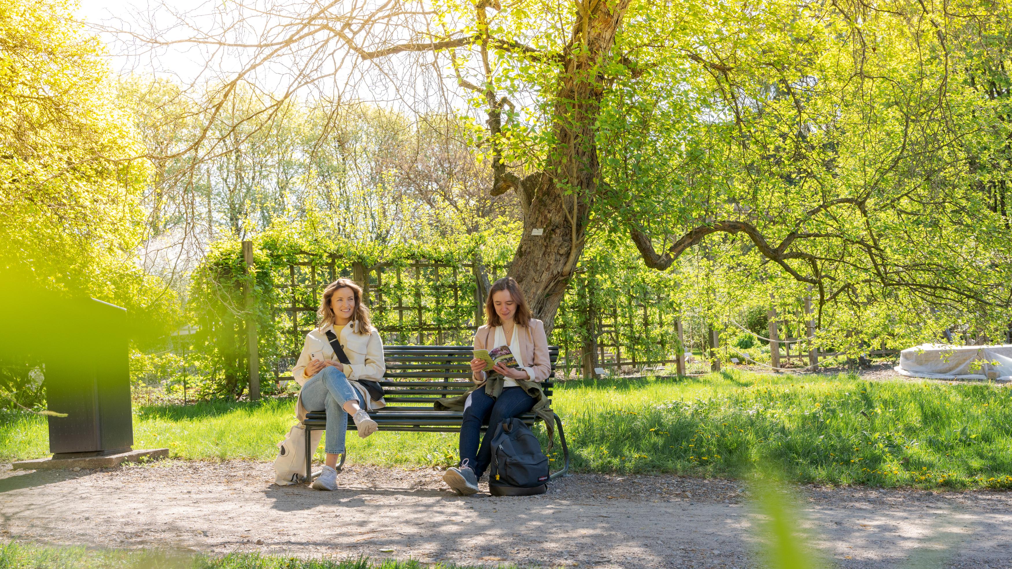 Two girls sitting on a bench in Oslo Botanical Garden