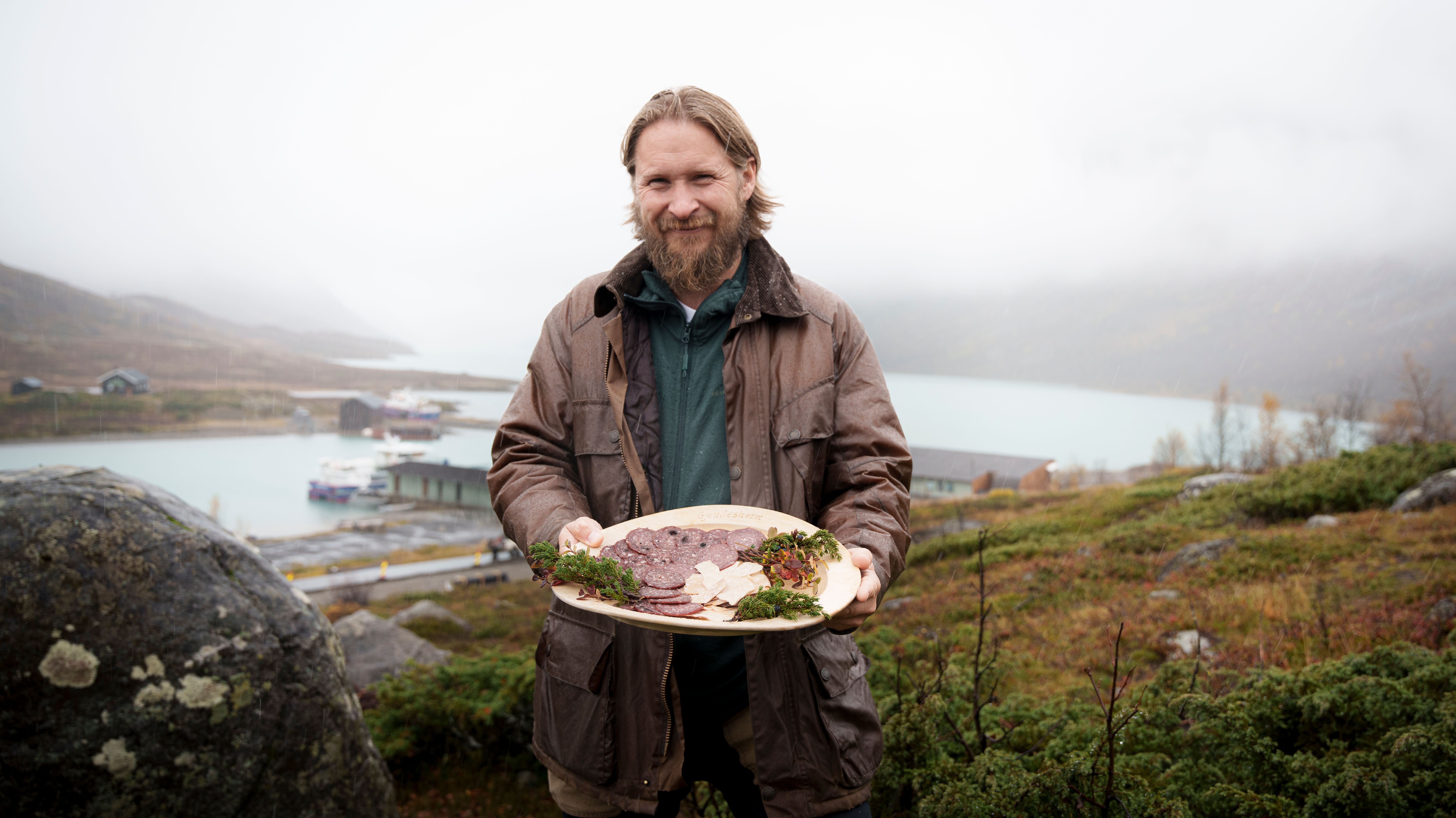 A man in nature holding a plate with local products.