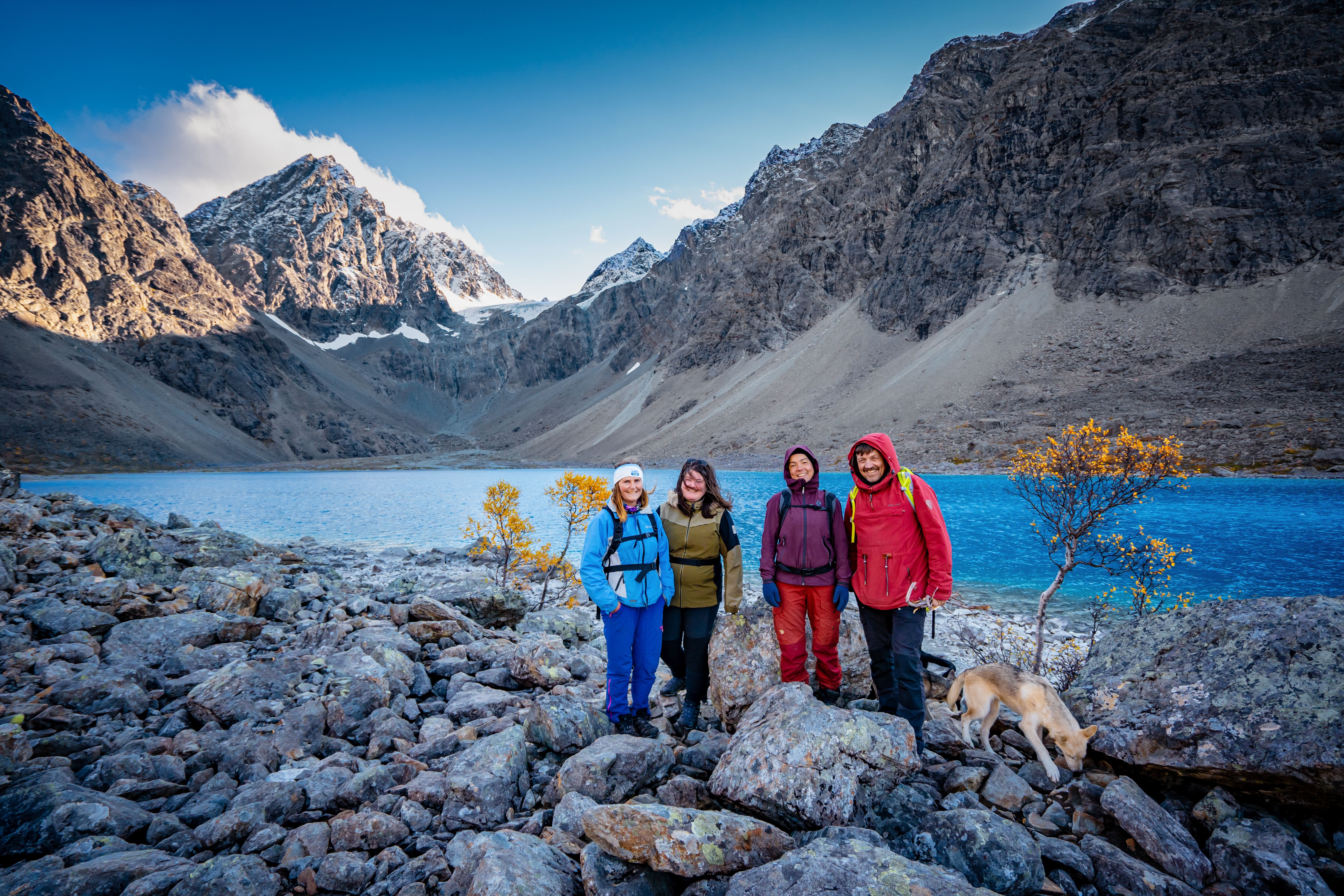 Four people in front of a blue lake and mountains