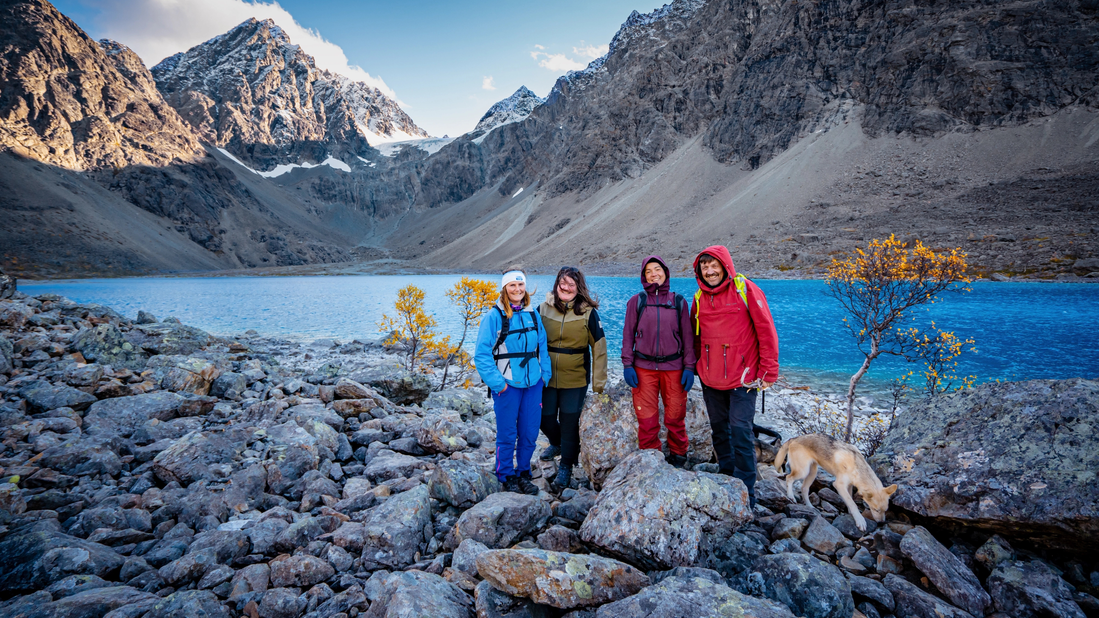 Four people in front of a blue lake and mountains