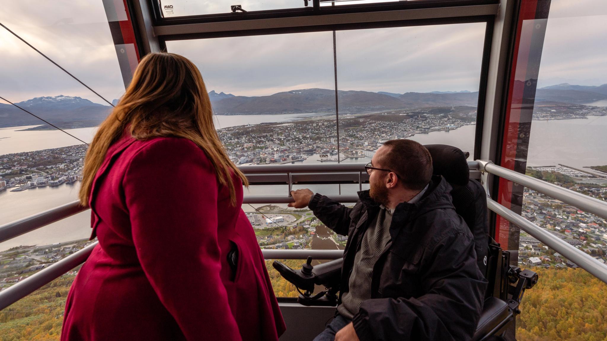 A woman and a handicapped man taking the cable car up to the mountain Storsteinen in Tromsø